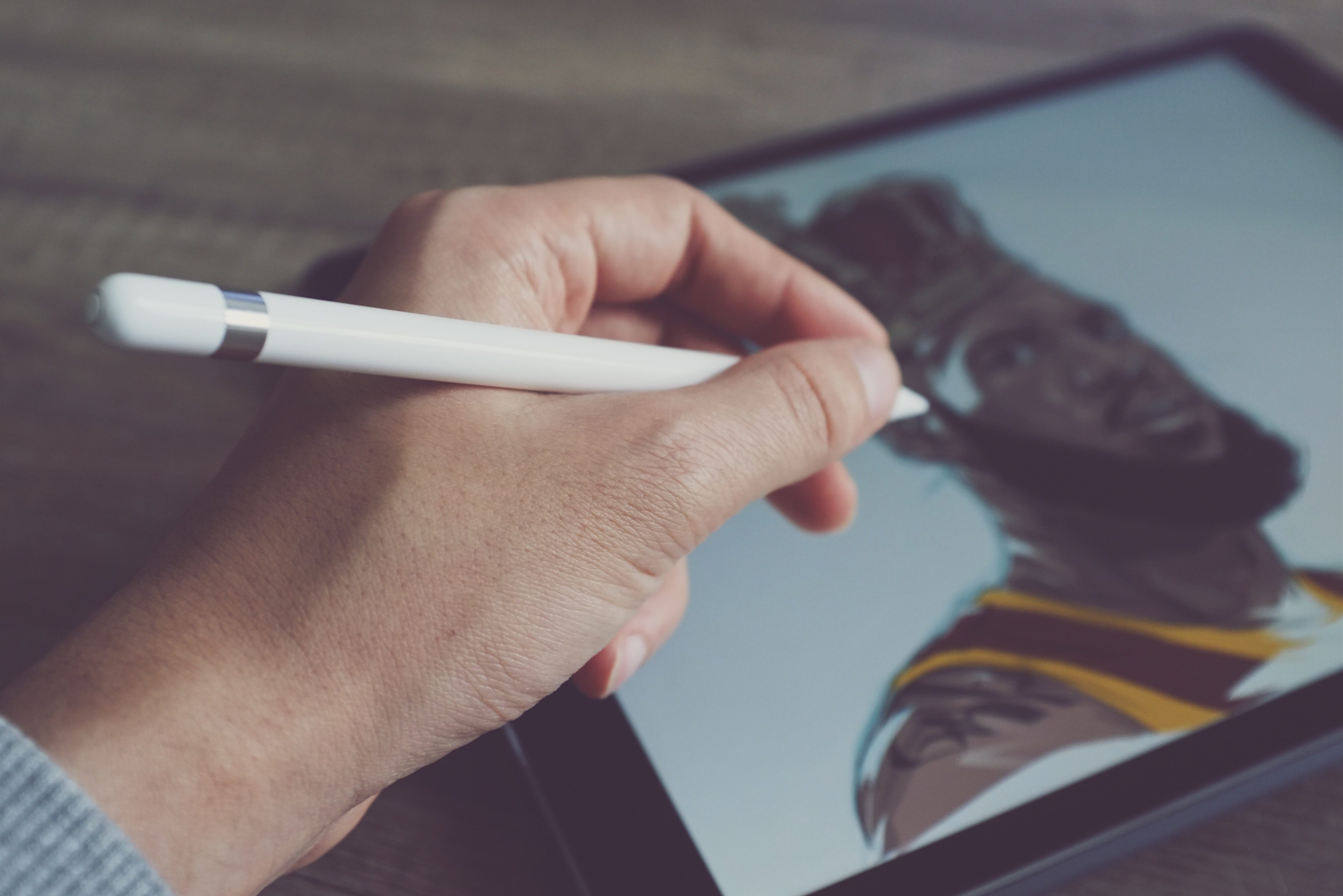 Man holding a stylus while using a drawing tablet.