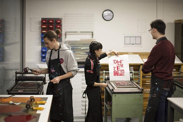 Three people working on projects in a print room.