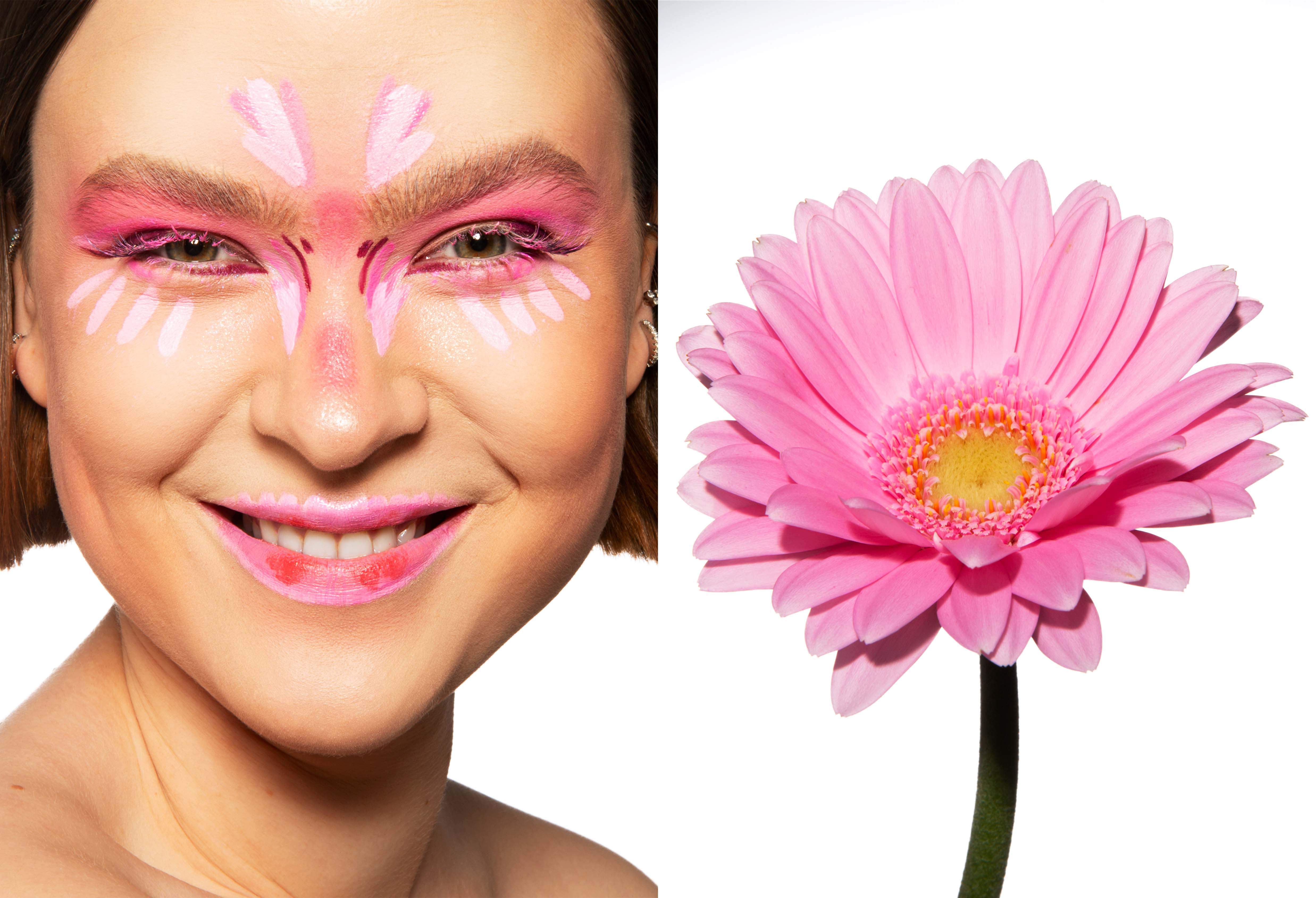 Person with floral, pink makeup smiling on the left, pink flower with yellow centre on the right, white background.