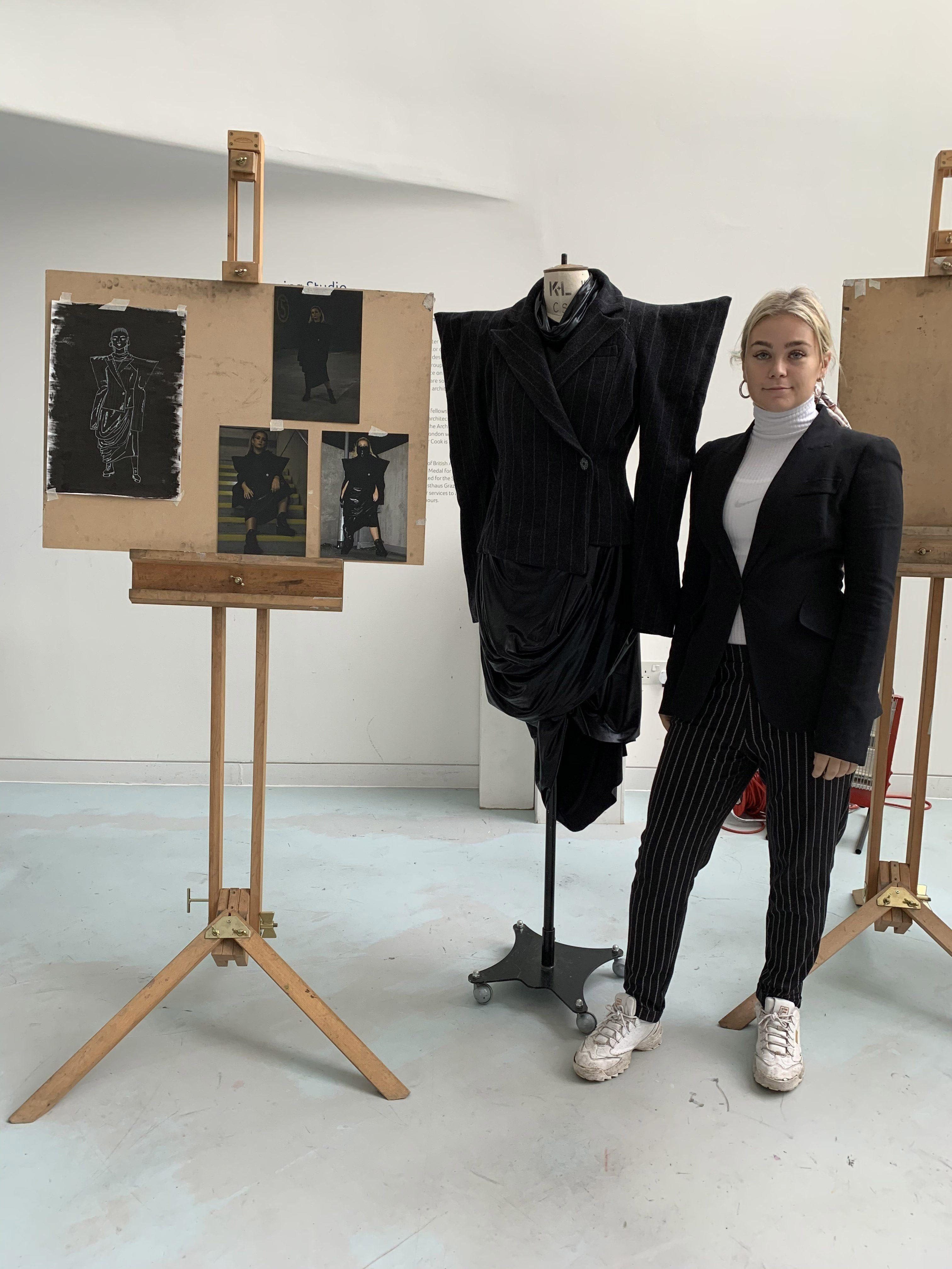 Portrait of A. Green with a series of photos on an easel and a garment on a mannequin.
