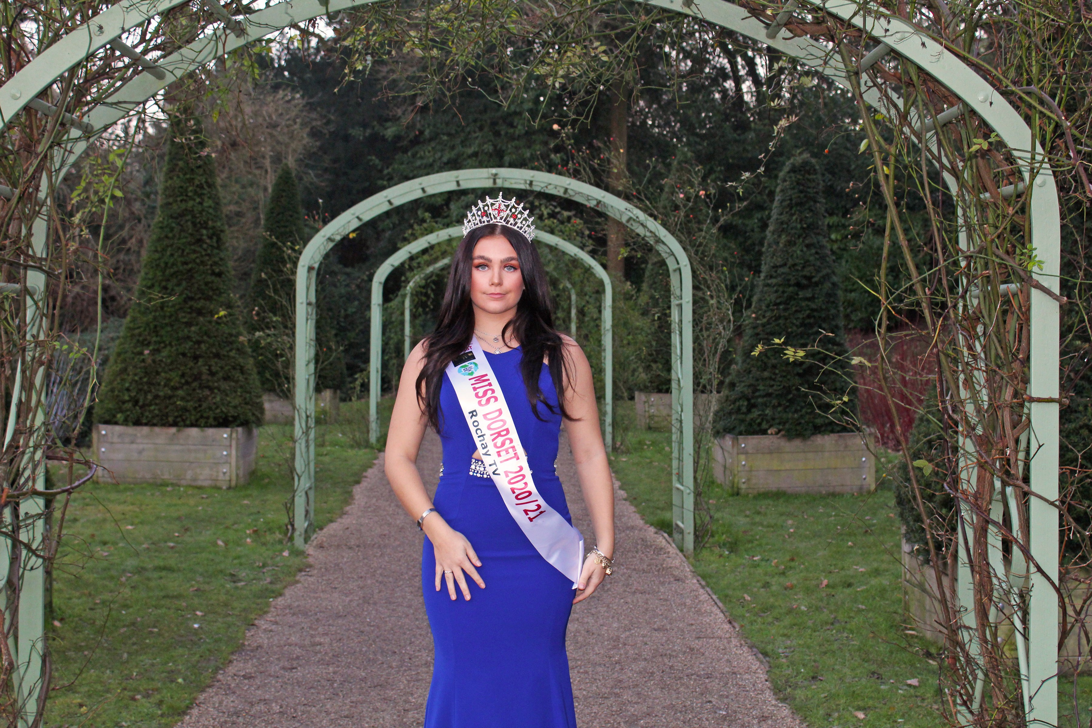 Portrait of A. Green with tiara and sash standing under a series of arches.