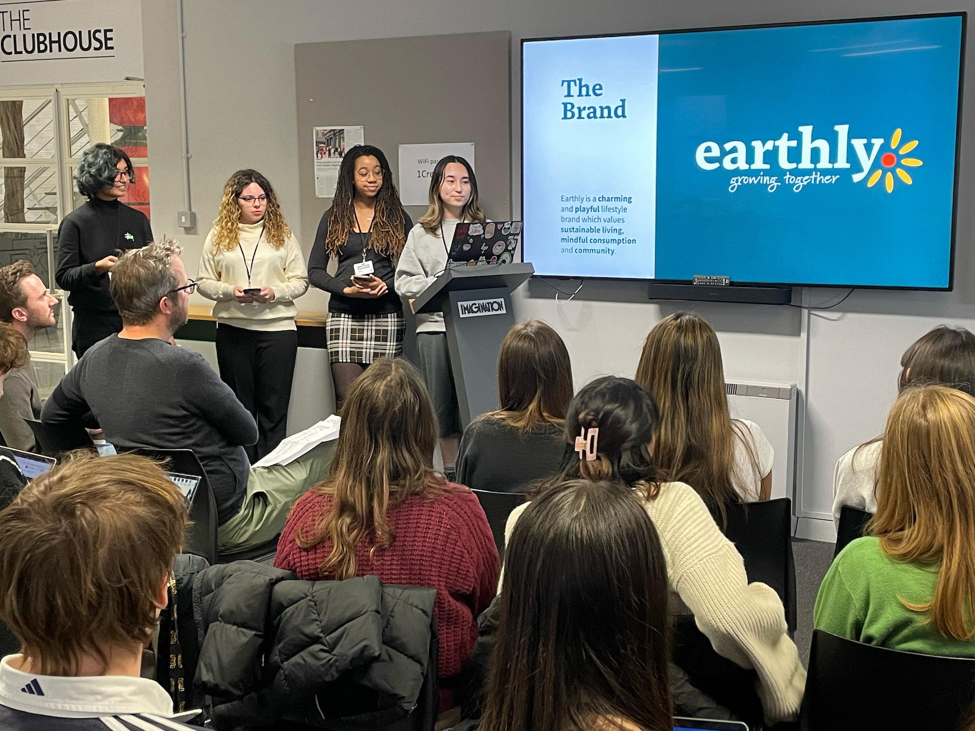 Student presentation with audience, display discussing the brand: 'earthly, growing together'.