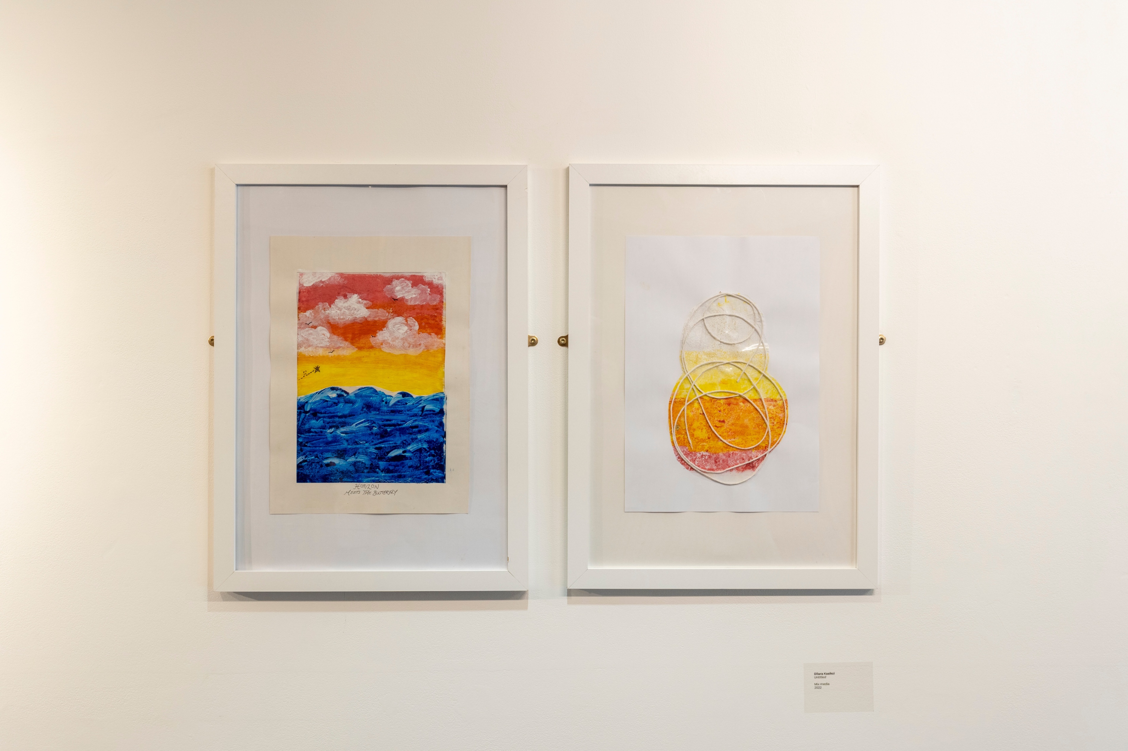 Exhibited student's artwork with one sunset painting and an abstract circular mix media piece.