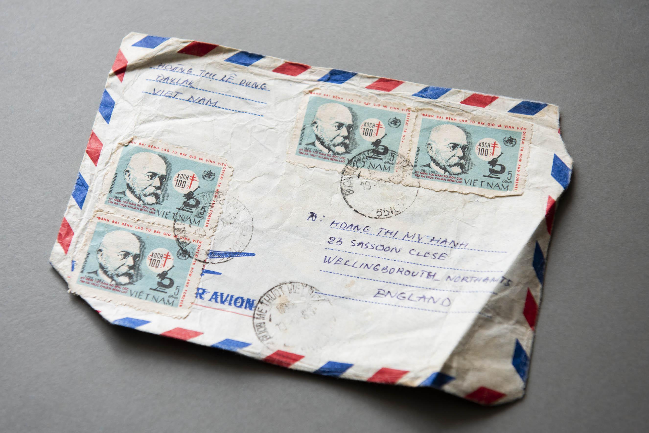 Close-up of a crumpled-up envelope with four stamps and handwriting on it.