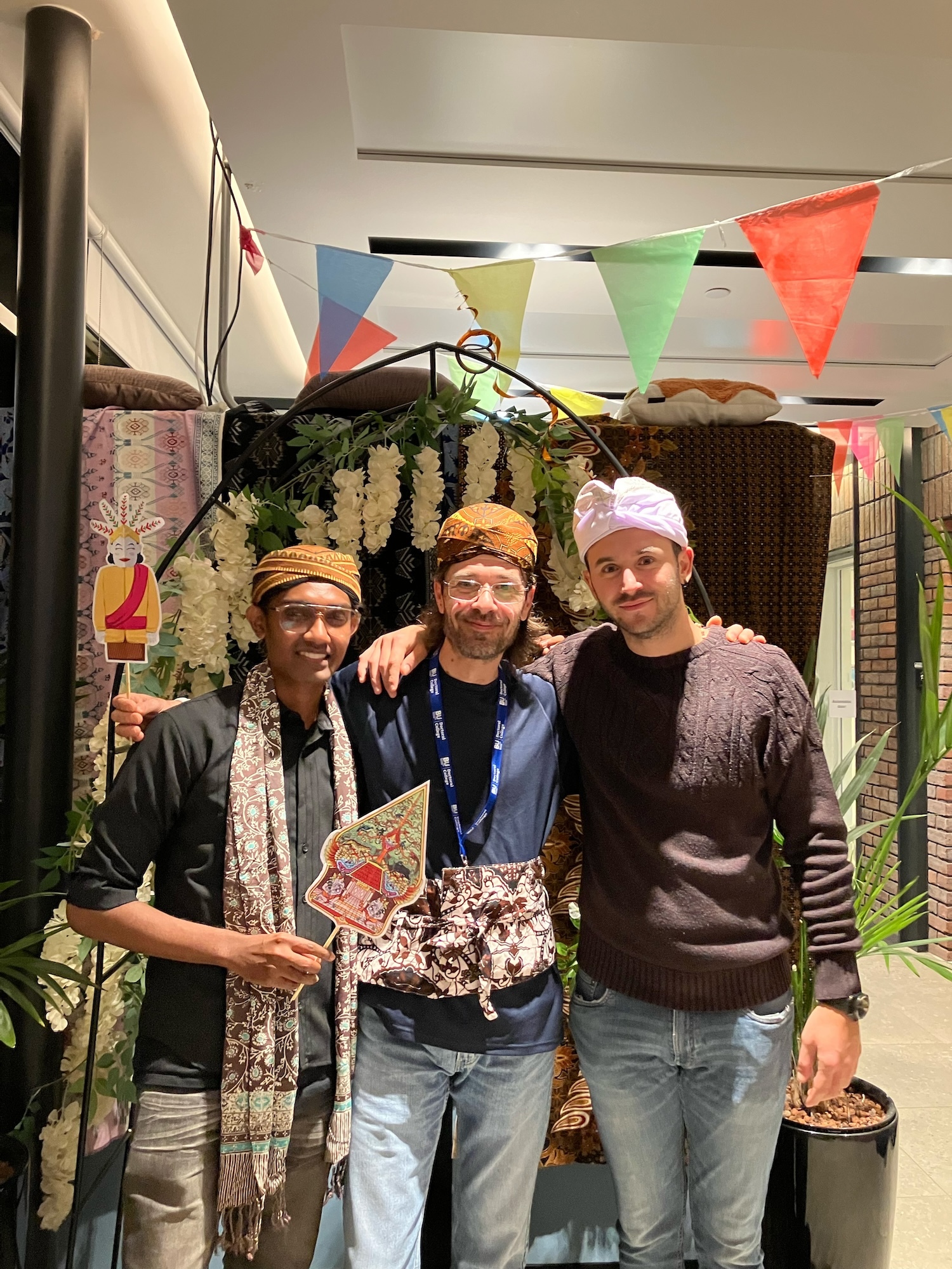 Three attendees of the Indonesian Cultural Harmony event at Madeira Road Halls of Residence wearing traditional Indonesian garments and posing for a photo.