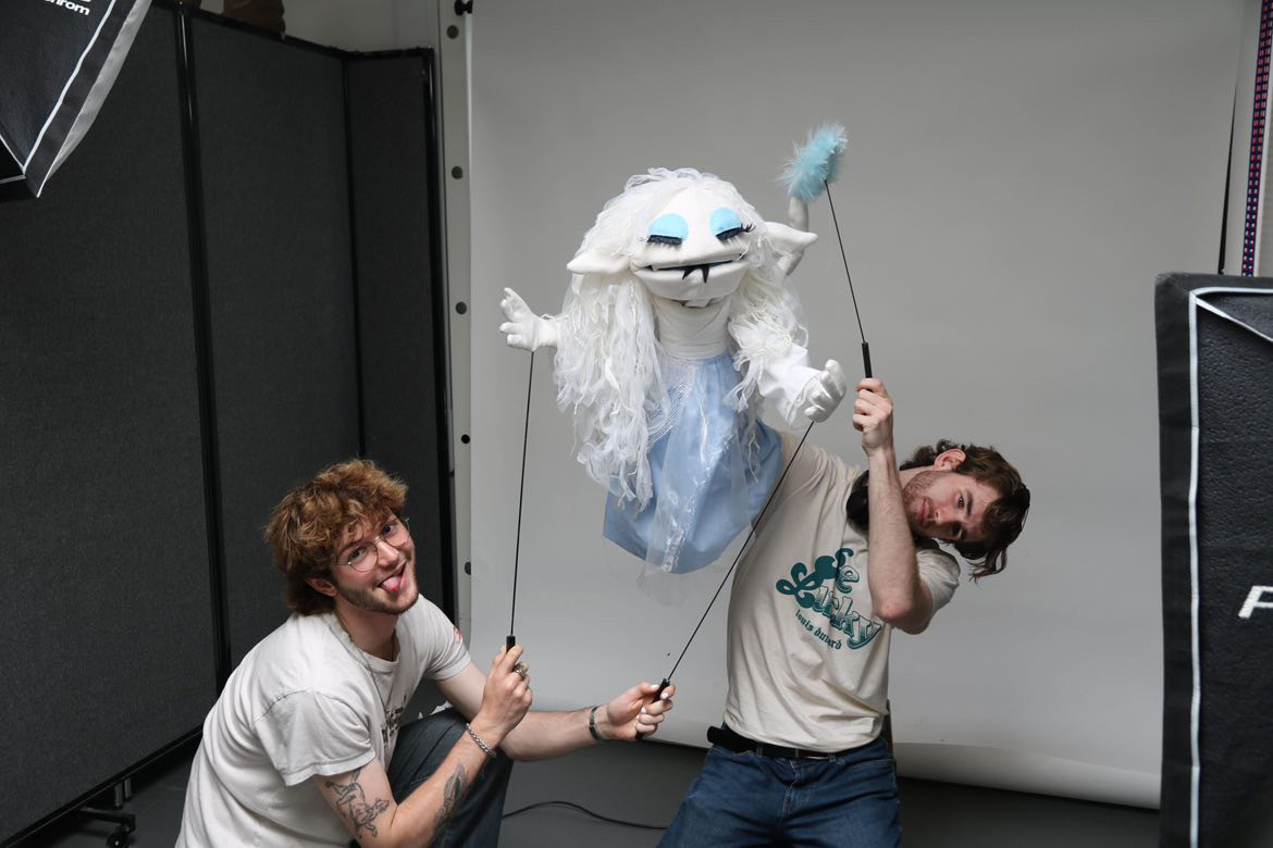 Two BA (Hons) Modelmaking students pose for a photo while holding an ice queen-style puppet.
