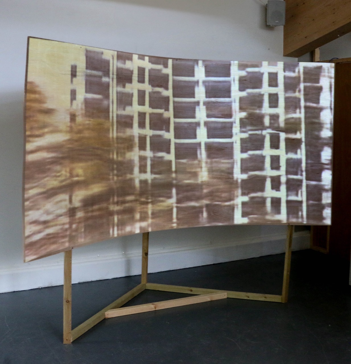 Still frame of a video with a building projected onto a wooden curved stand.