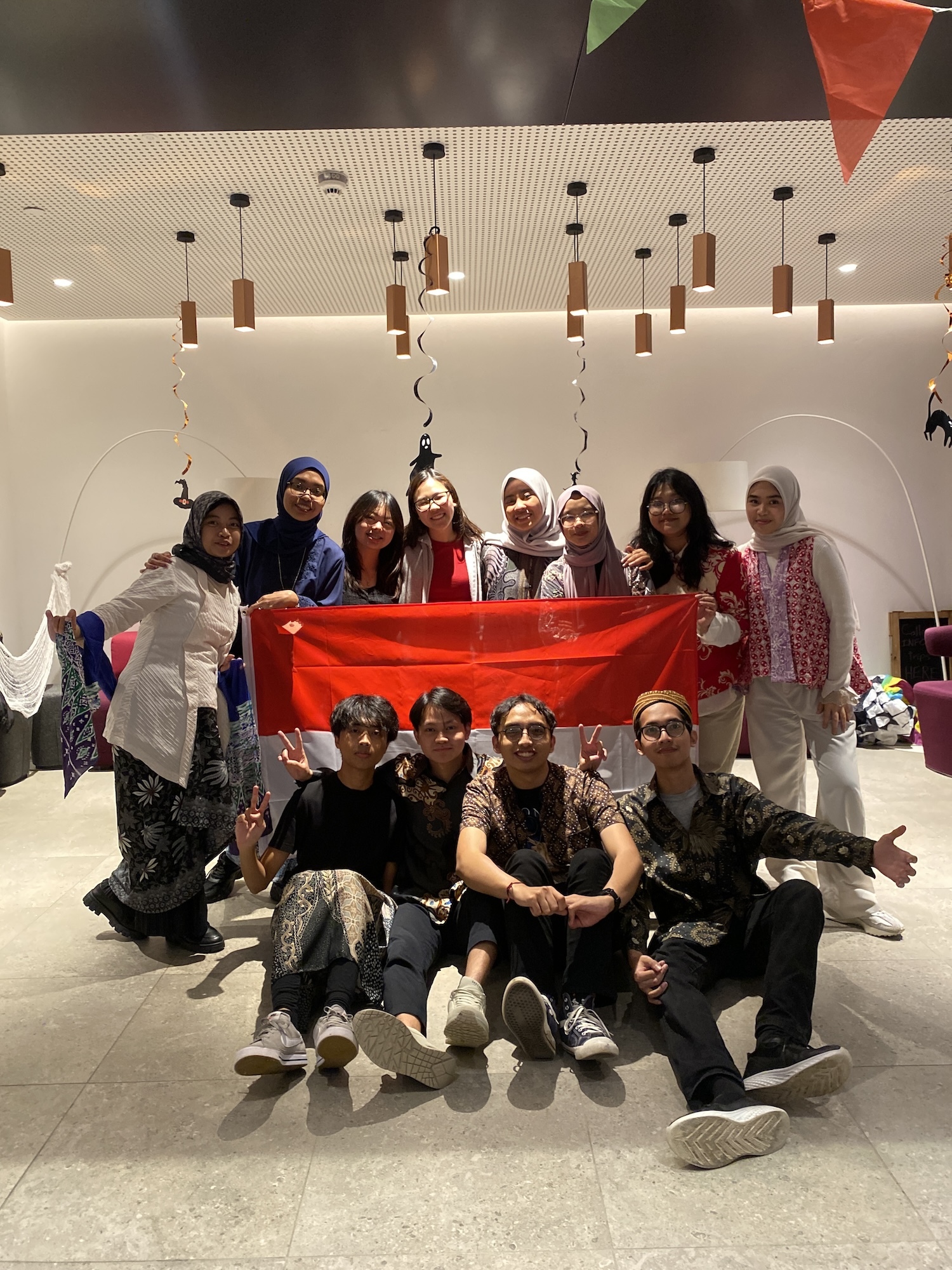 A group of Arts University Bournemouth students gather and pose for a photo with an Indonesian flag at the Indonesian Cultural Harmony event at Madeira Road Halls of Residence.