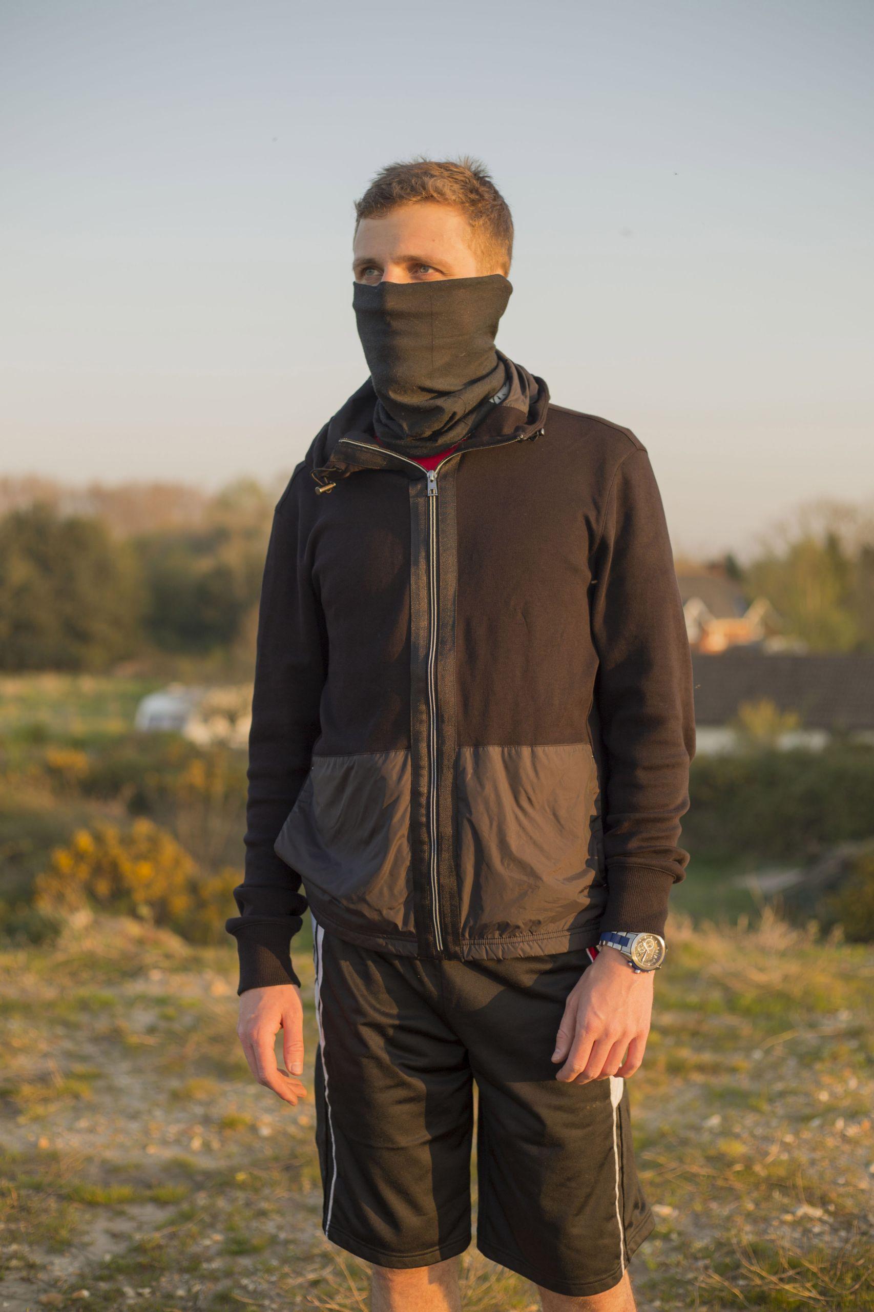 Person in sportswear and a snood stands on a heathland.