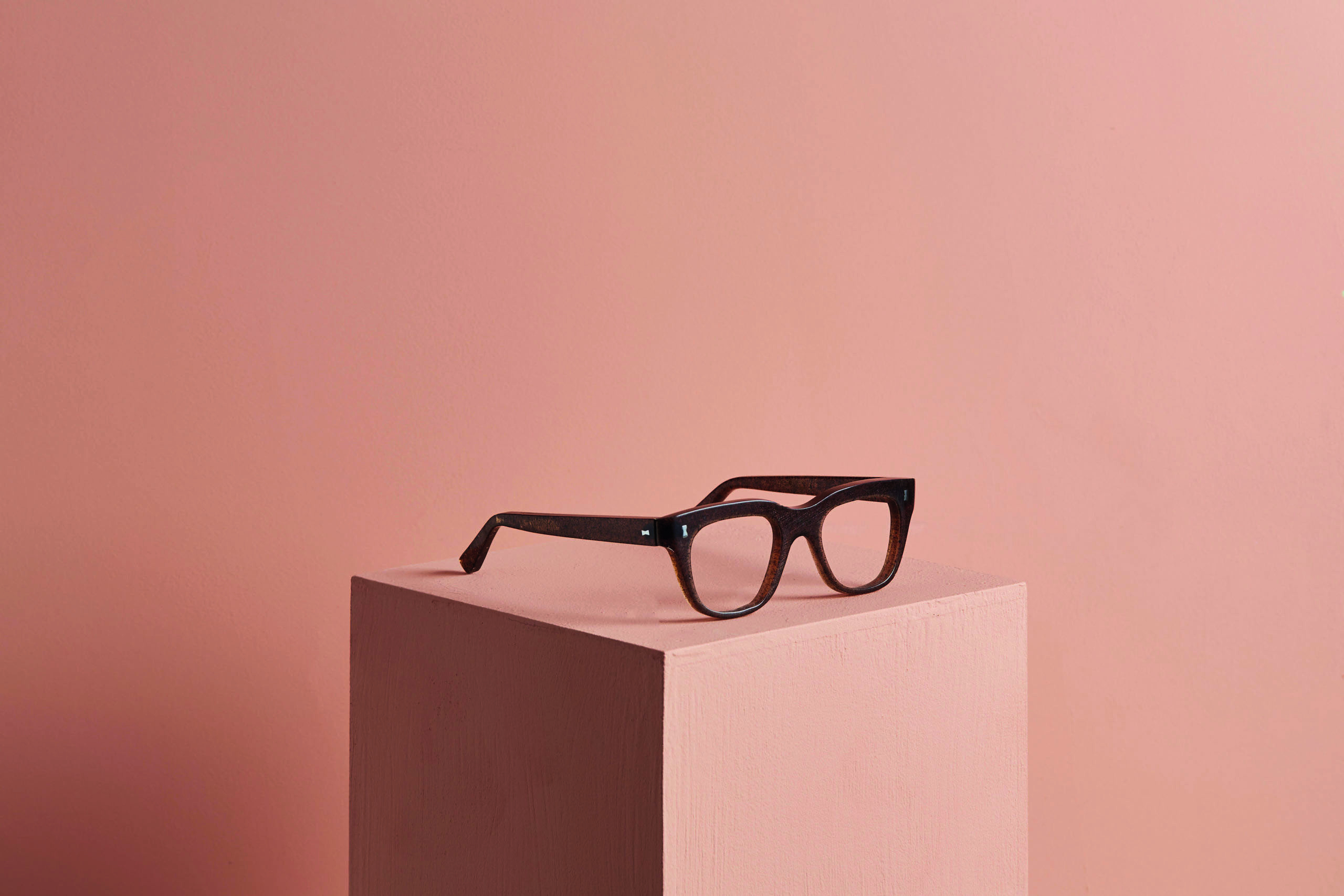 A pair of glasses rest on a cube block