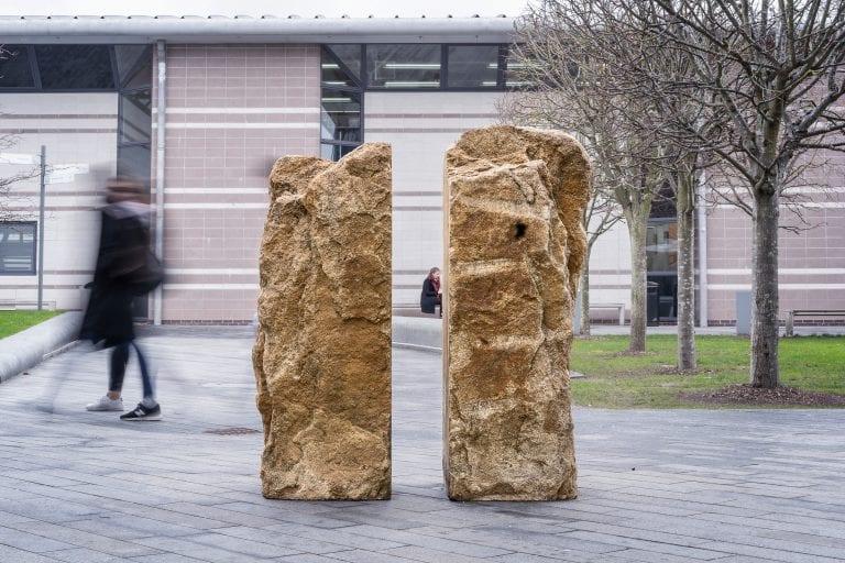 Two stone sculptures with a courtyard behind them.