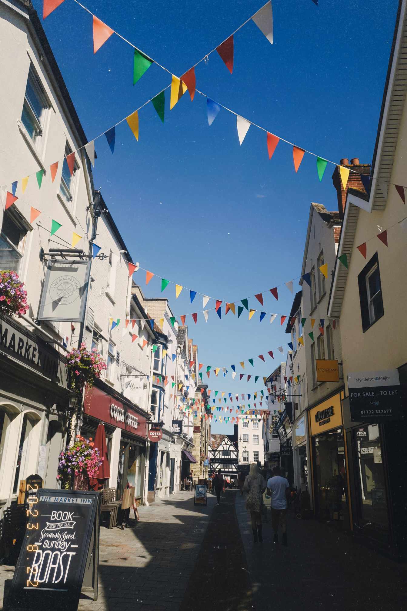 A sunny street with colourful flags and a blue sky.