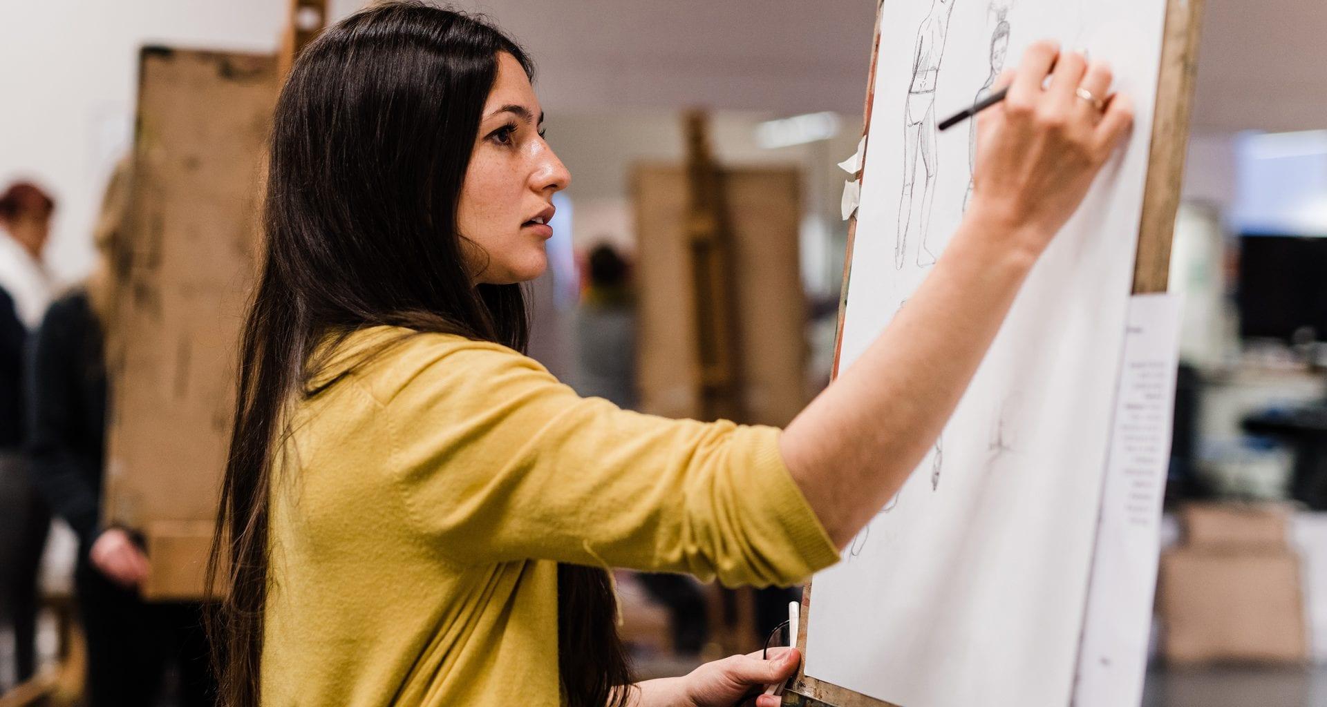 Women drawing with pencil on an easel