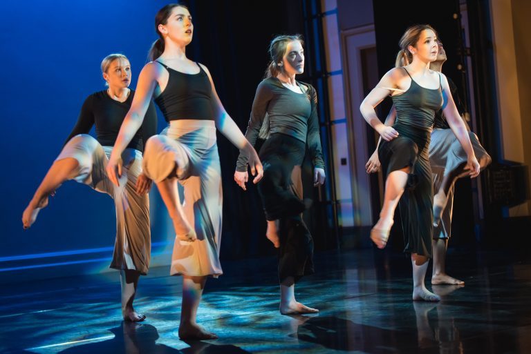 Five dance students in the middle of performing a routine on stage