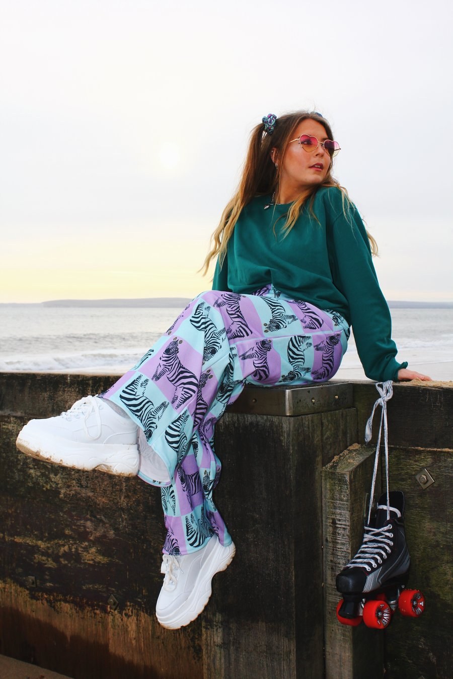 Person sat on a beach groyne, kicking legs out in front of them