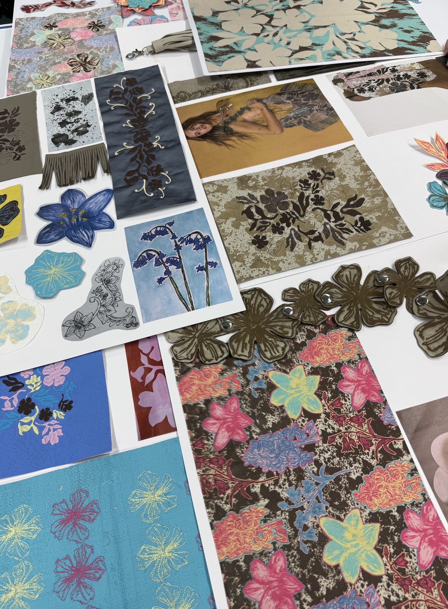 Various samples of colourful textiles designs on display on a white tabletop.