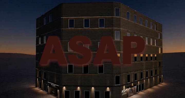 A modern, multi-storey building with dark cladding and large windows, positioned at a slight angle. The ground level features a sign with the text 'ASAP' prominently displayed. The scene is illuminated by soft lighting, suggesting dusk.