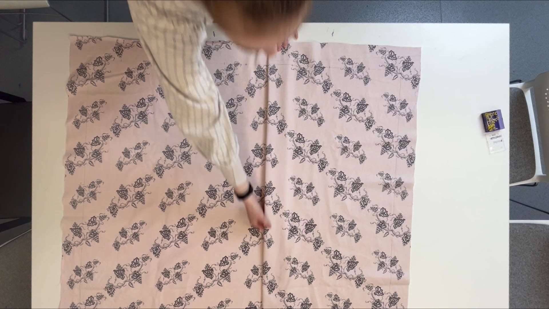 Top-down view of a person working on pink-brown floral fabric.
