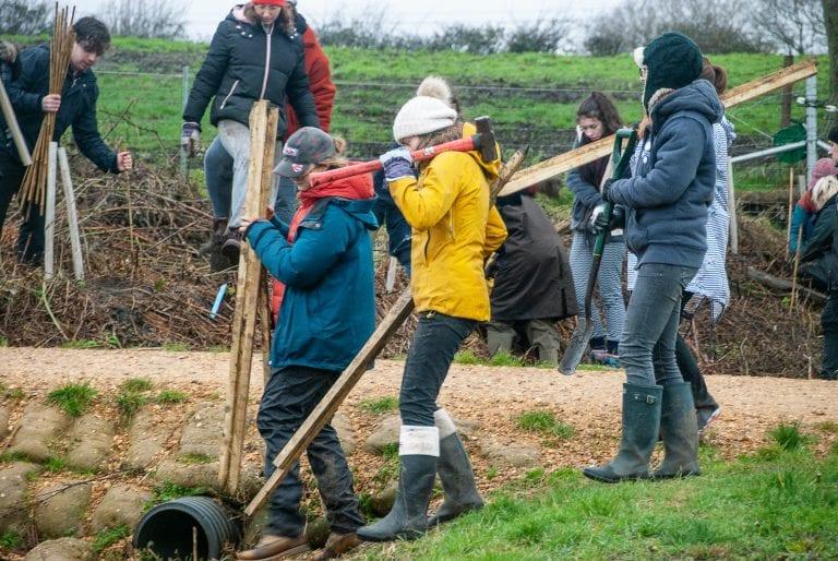 Several people walk down a slope carrying tools