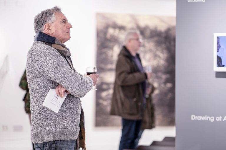 A person with their arms folded looks at a gallery exhibit.