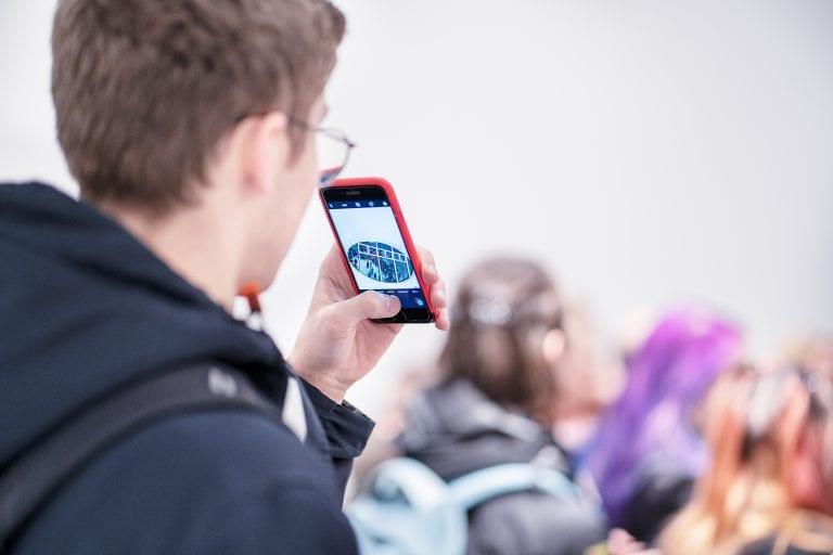 Back view of a person taking a photo on their phone.