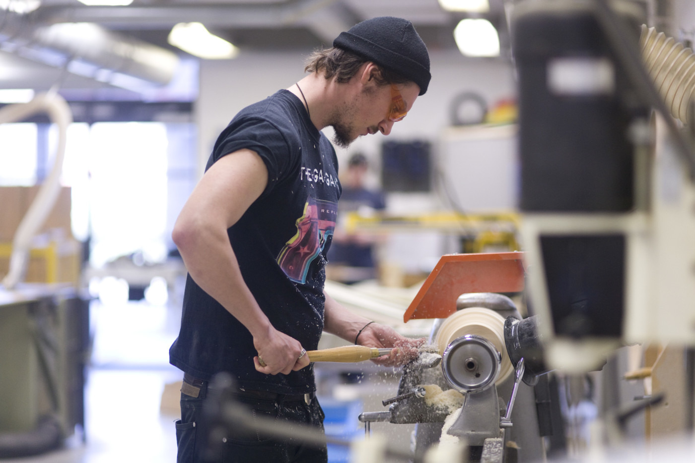 A man viewed from the side in a workshop working with a machine.