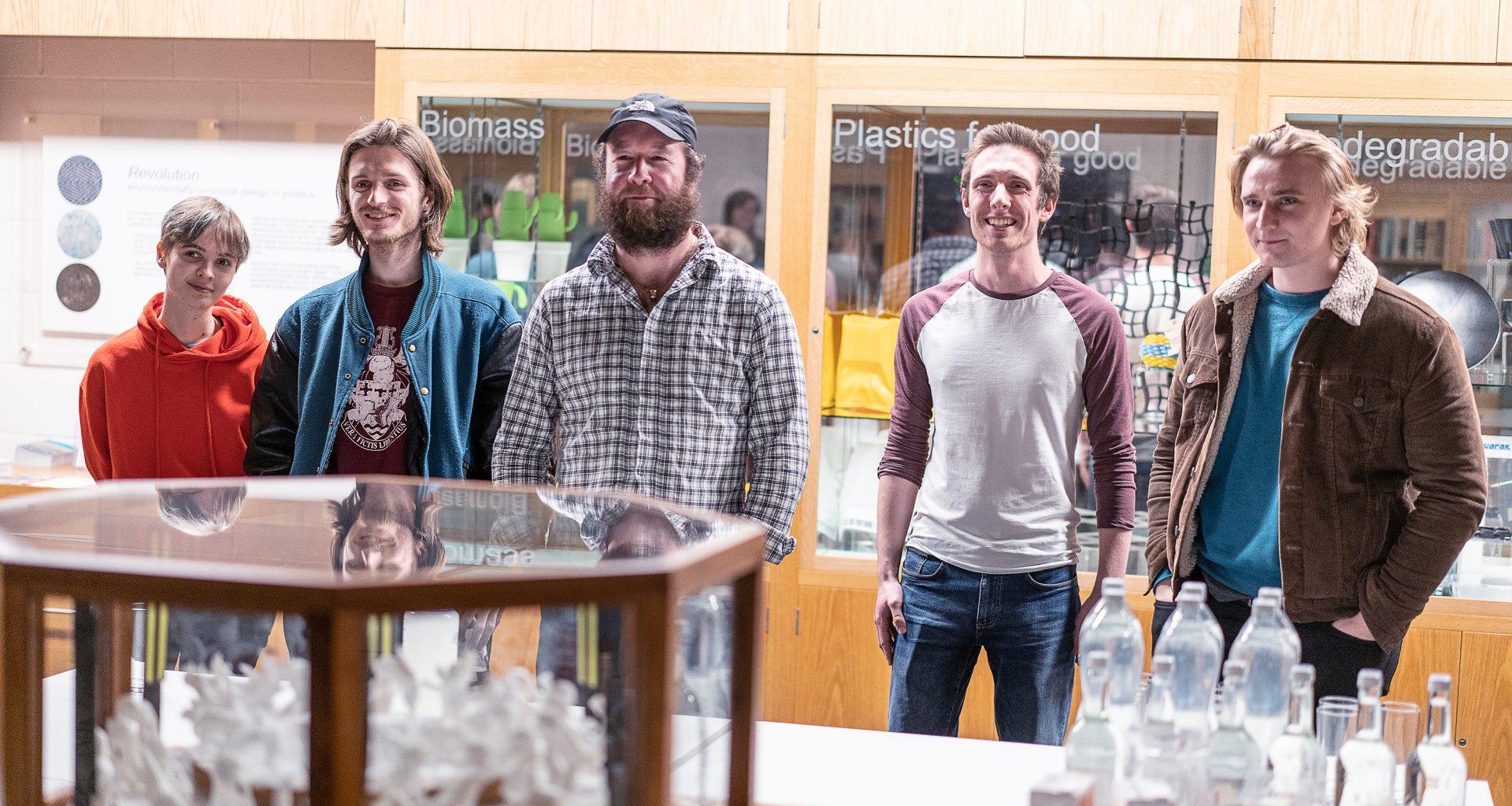 Five people stand behind a table with two displays on them.