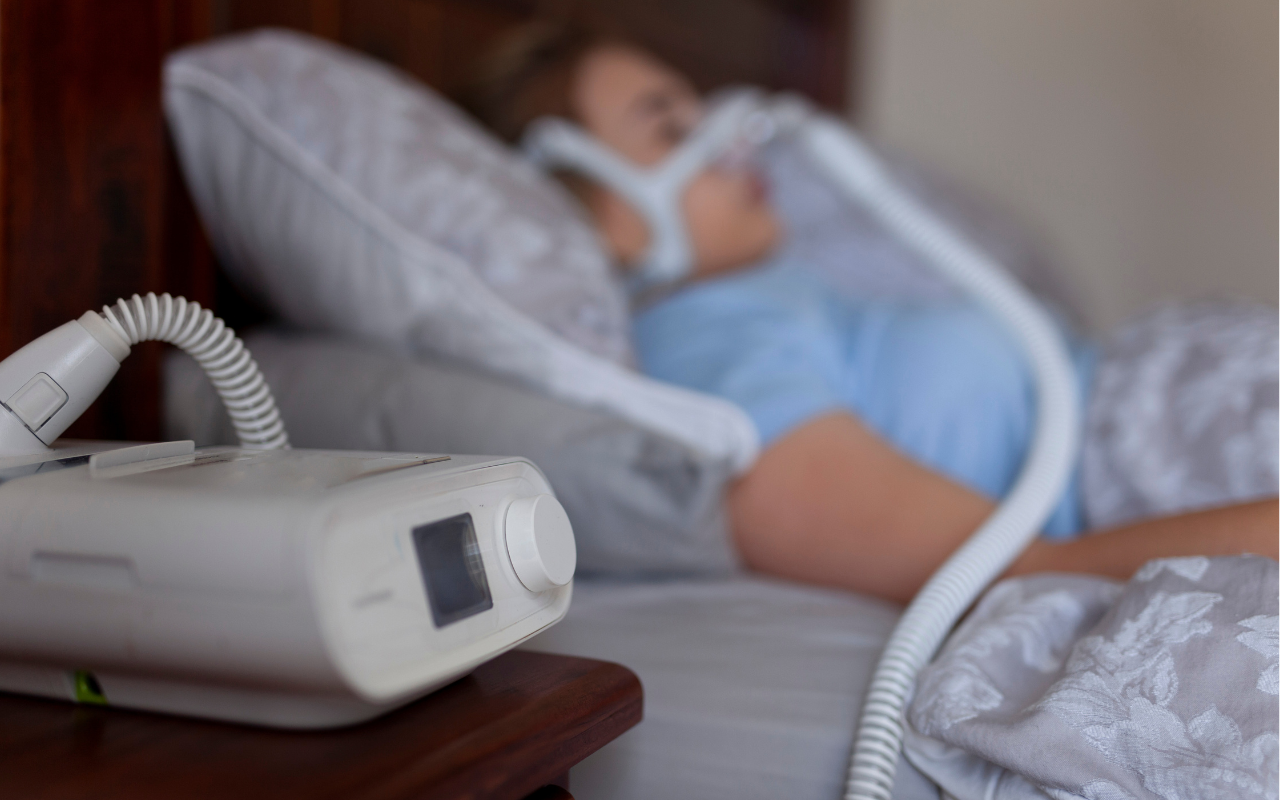 A woman in bed using a cpap machine as she sleeps