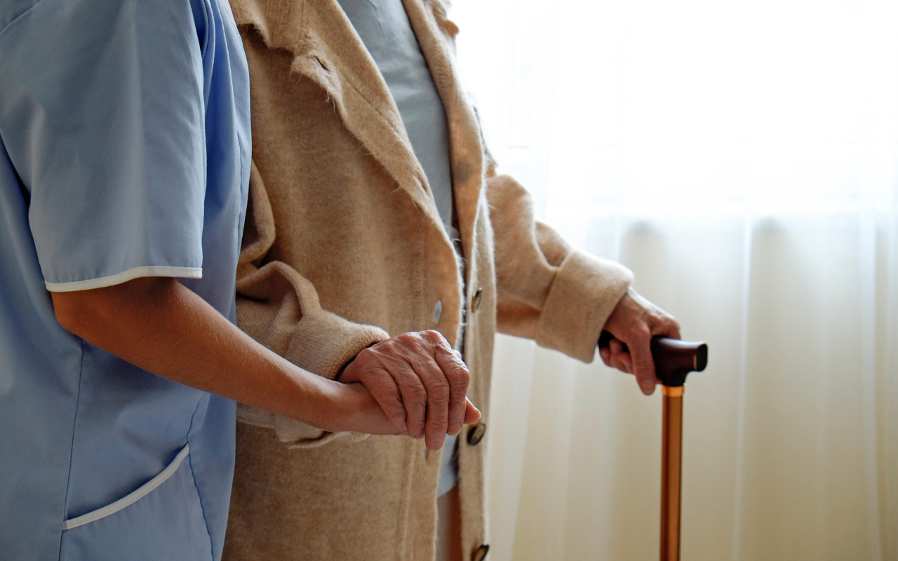 A person with dementia walking supported by a nurse