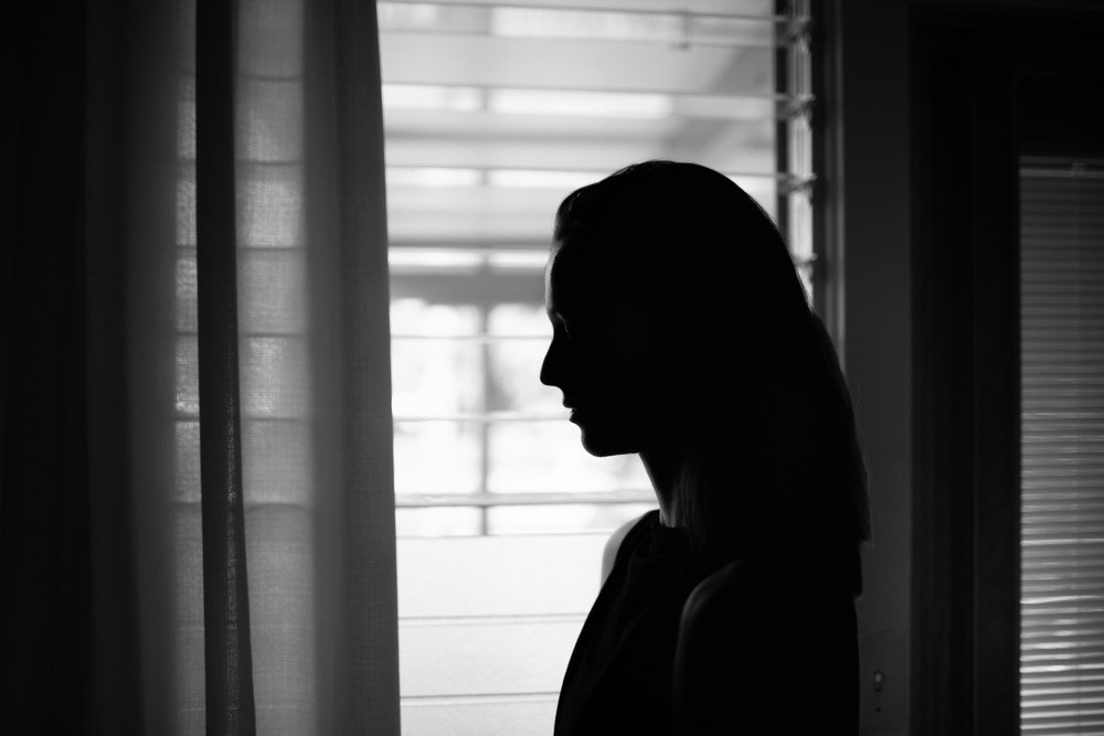 Silhouette of a woman by the window, experiencing severe mental health