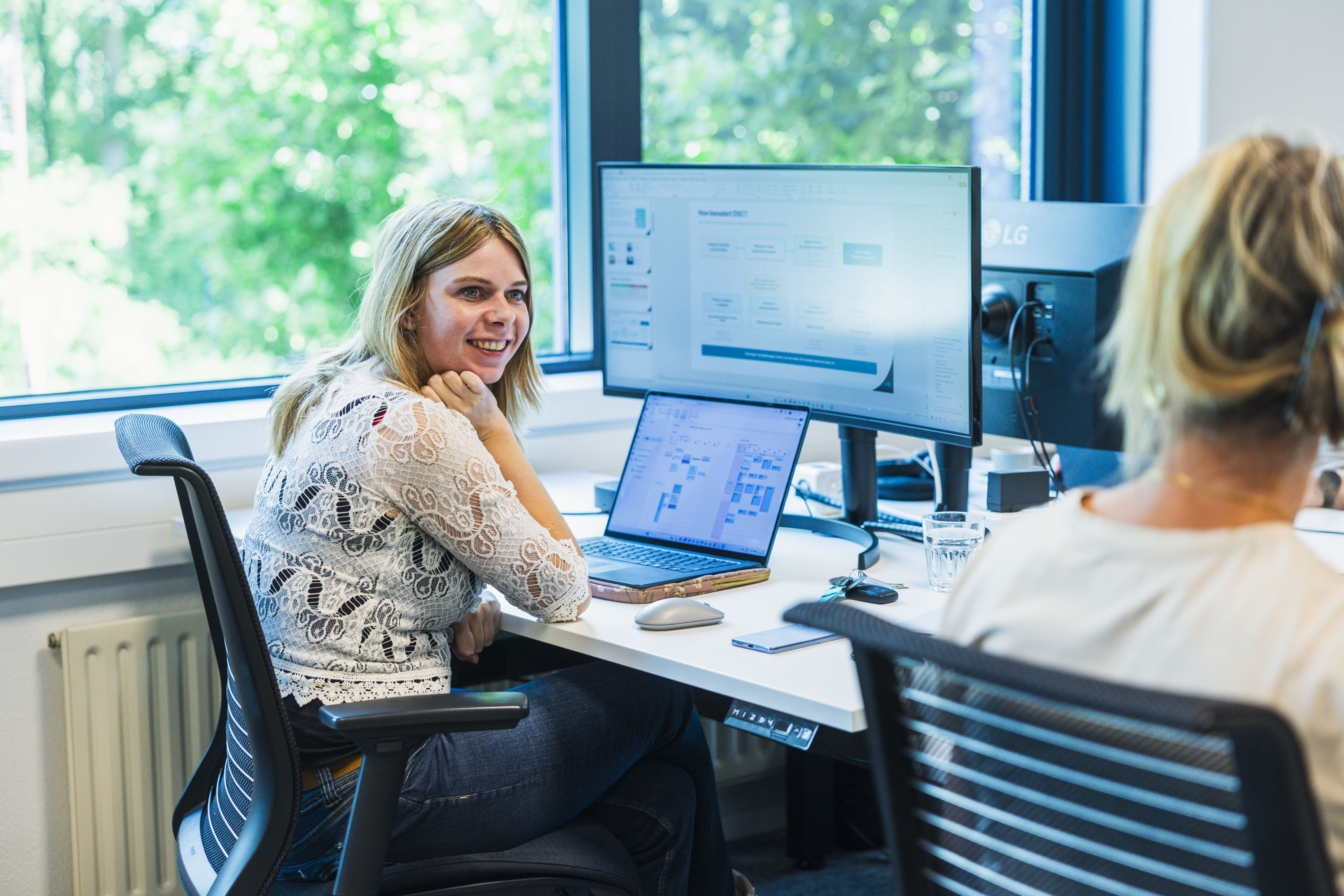 Twee collega's aan een bureau met een dashboard op het scherm