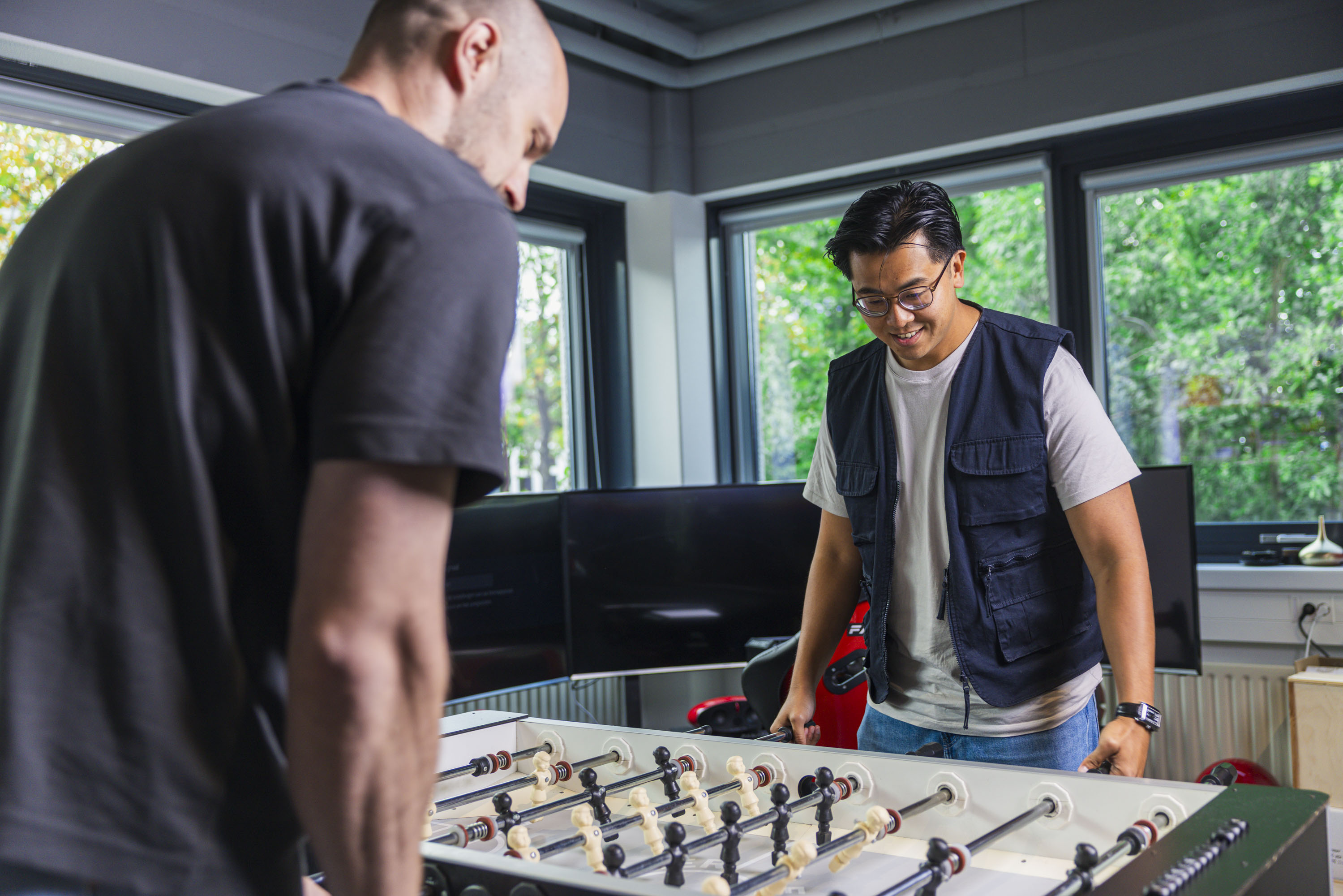 Two colleagues playing table football in the office