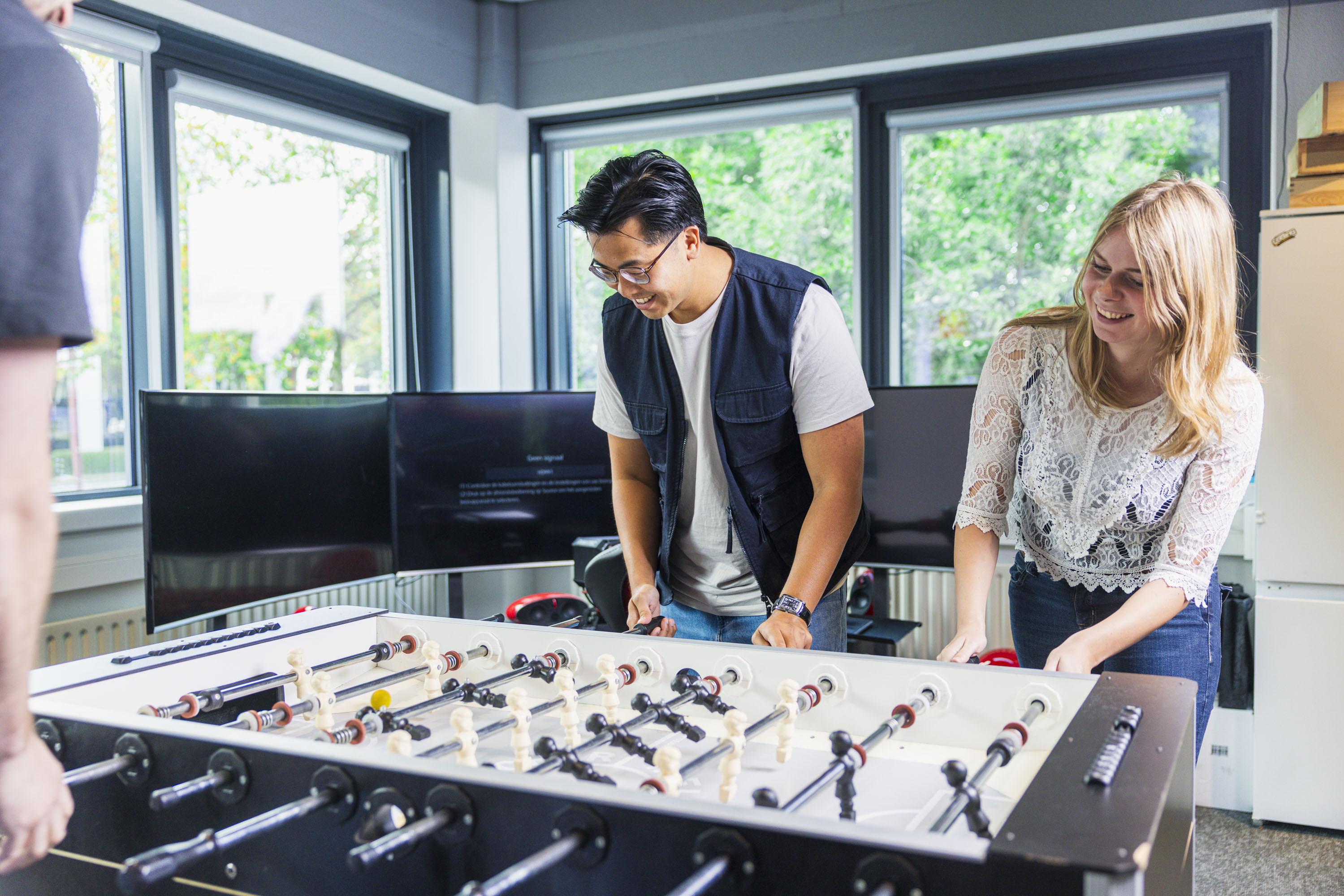 Two colleagues playing table football in the office