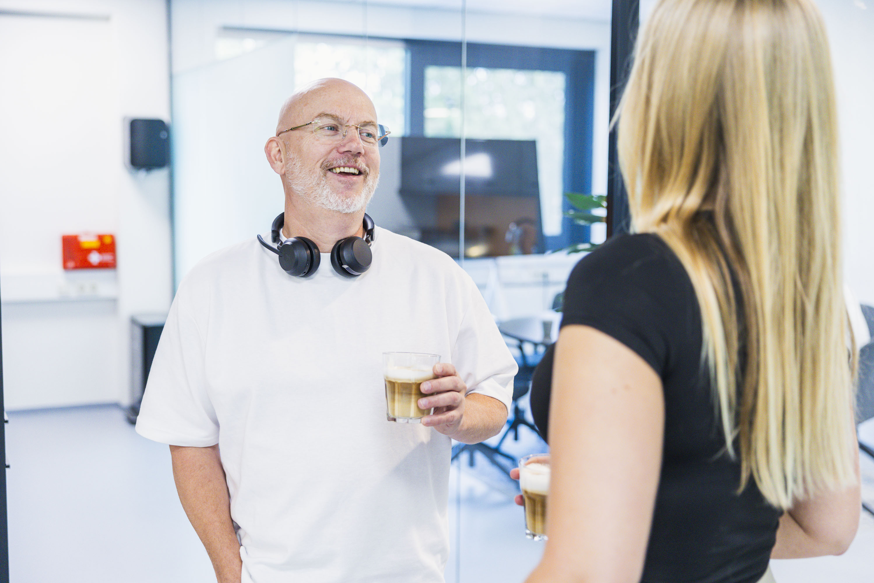 Two colleagues chatting with drinks in the office