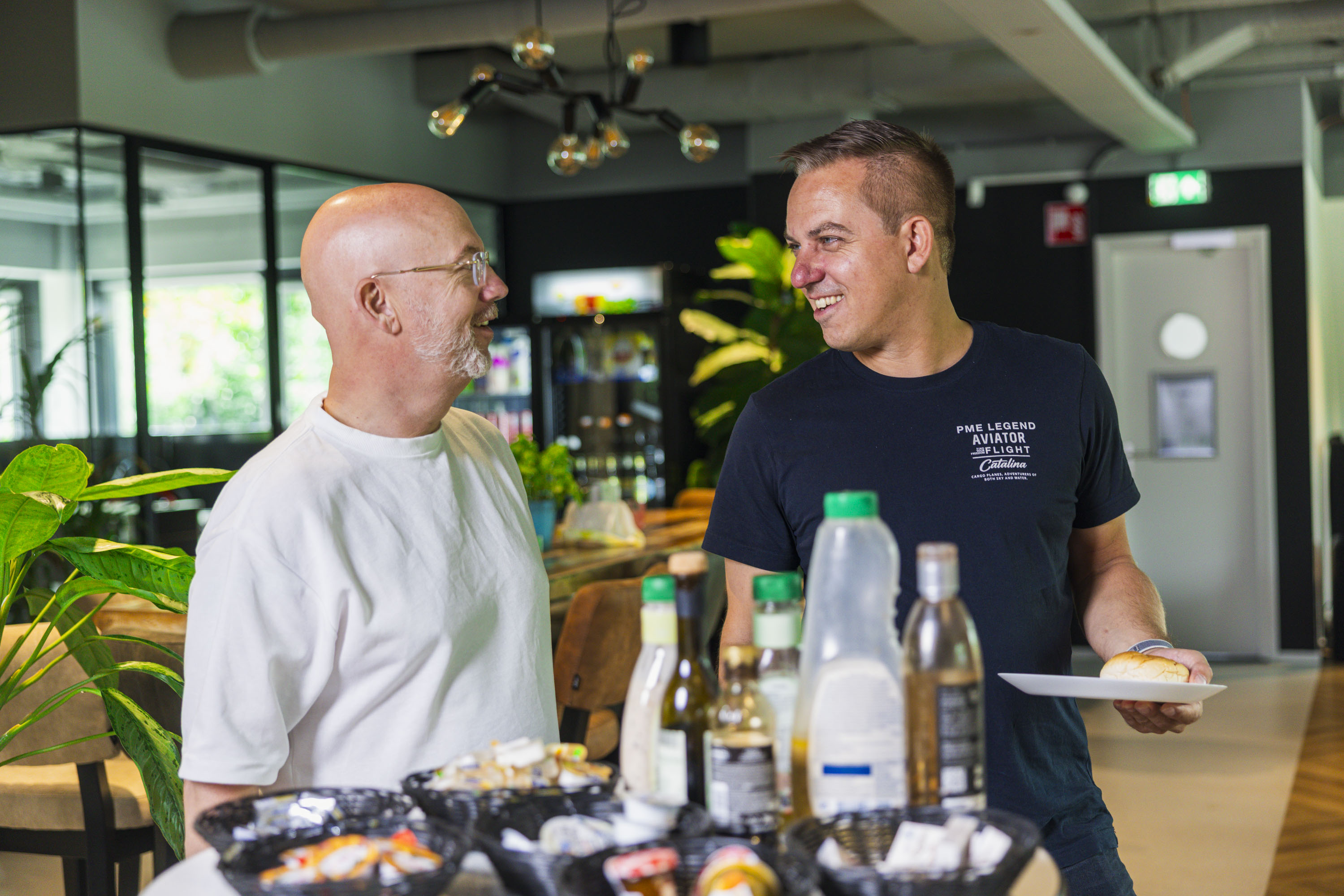 Two colleagues chatting beside the lunch buffet