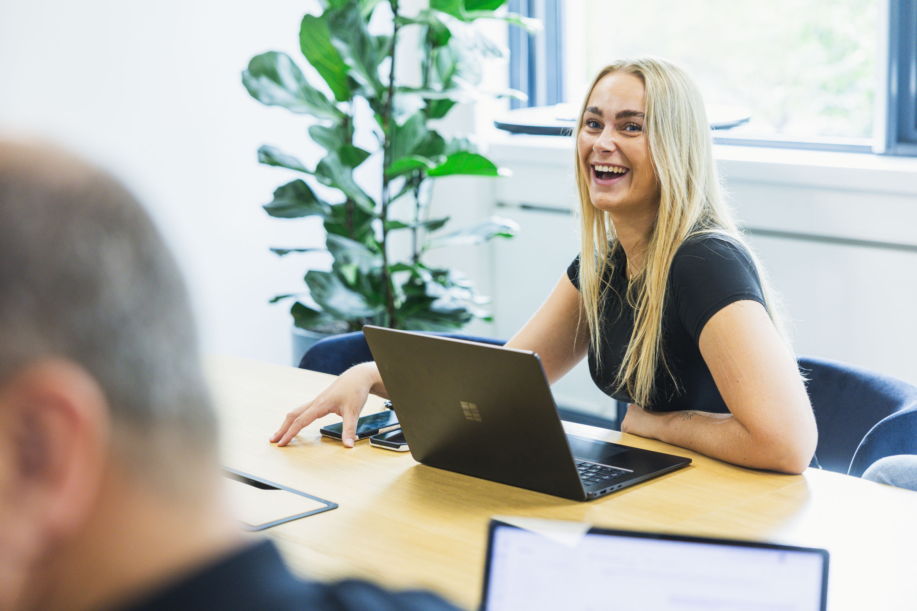 Two colleagues talking across a desk with laptops