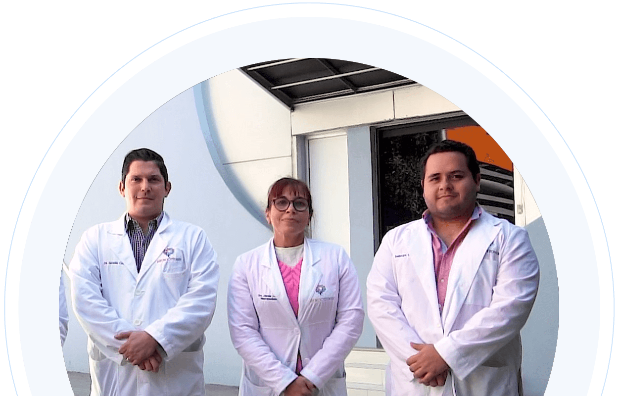 Three team members in white lab coats standing infront of the NeuroCytonix building