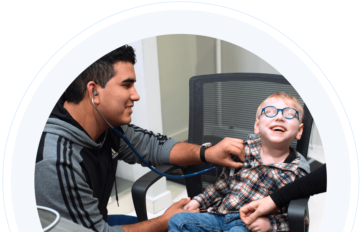 Healthcare giver using a stethoscope to listen to a young boy's heart
