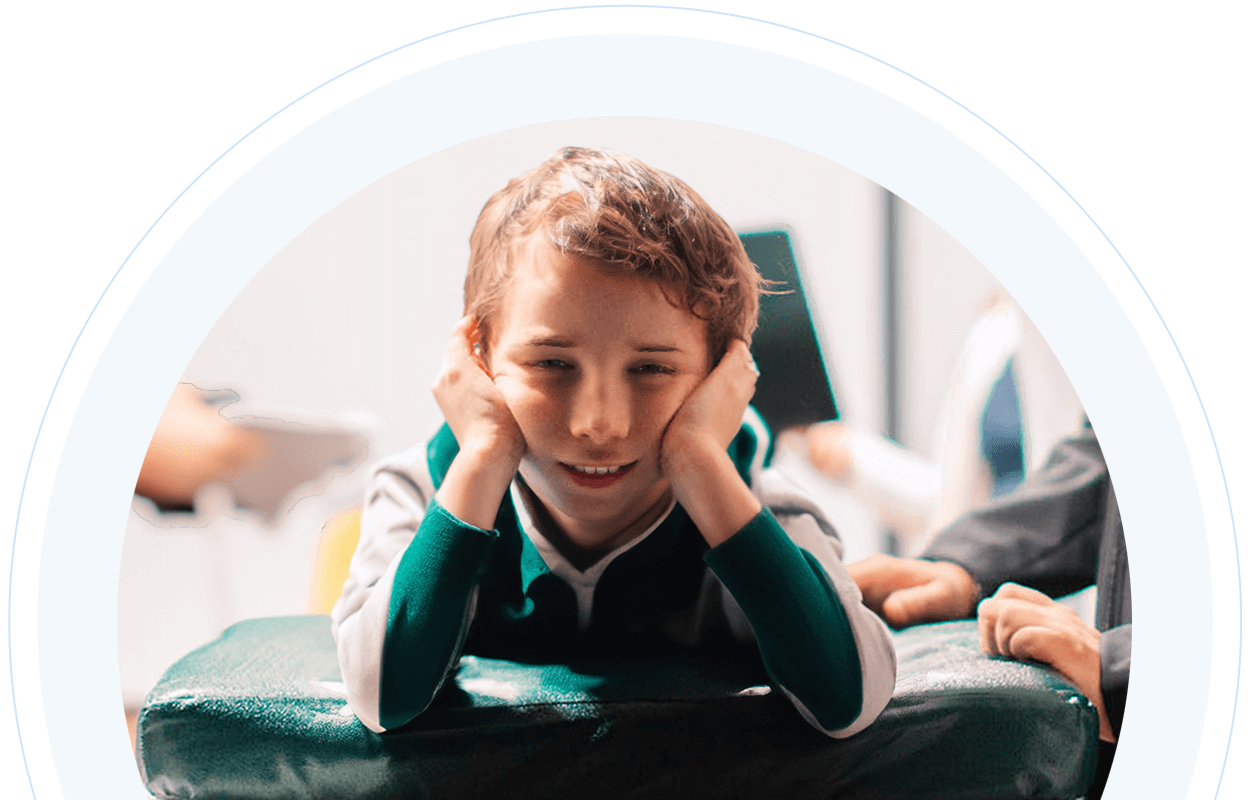 Boy smiling and laying down in NeuroCytonix device with his head in his hands smiling