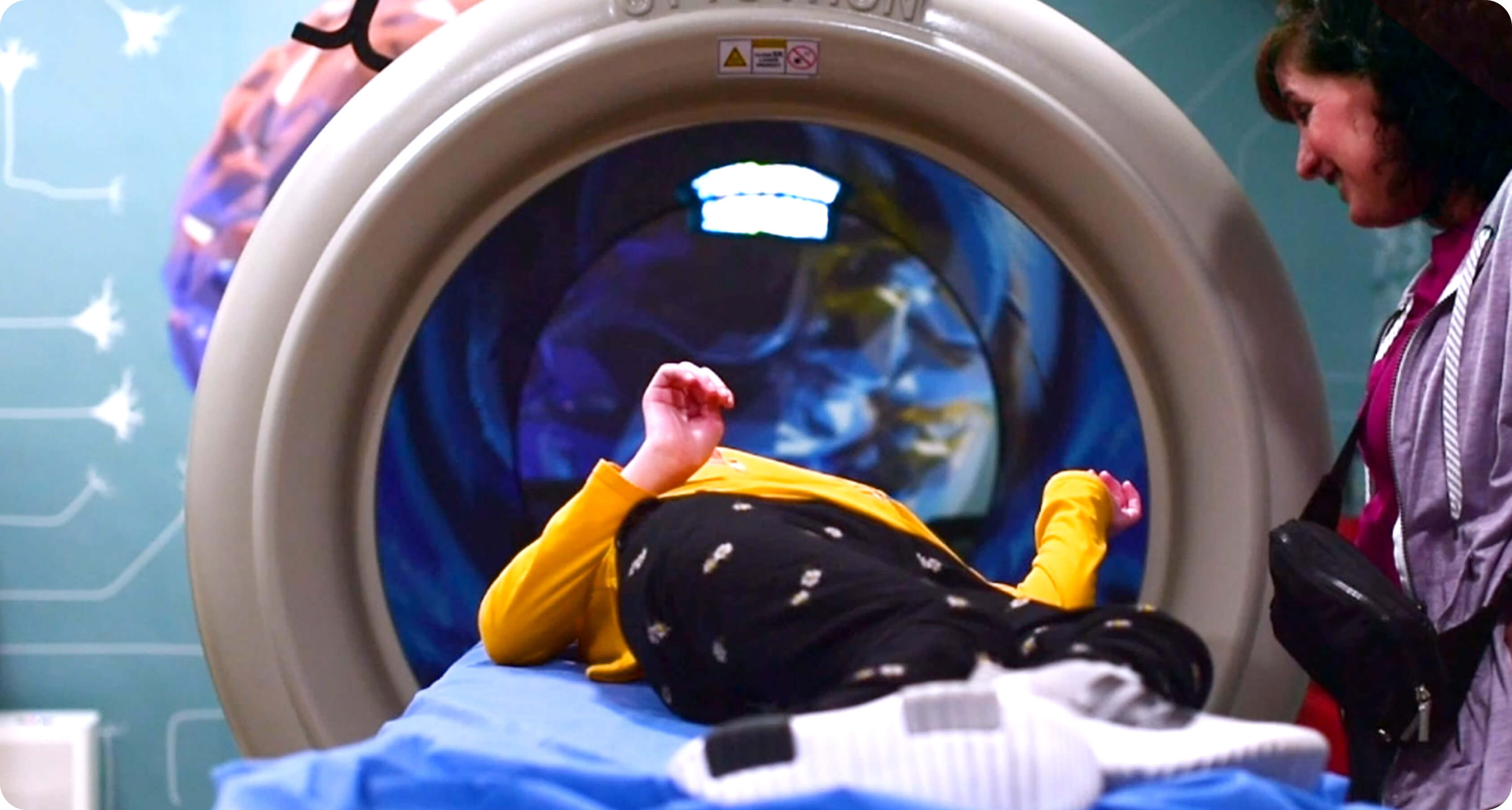 Teenage girl laying down in NeuroCytonix device with her mother by her side.