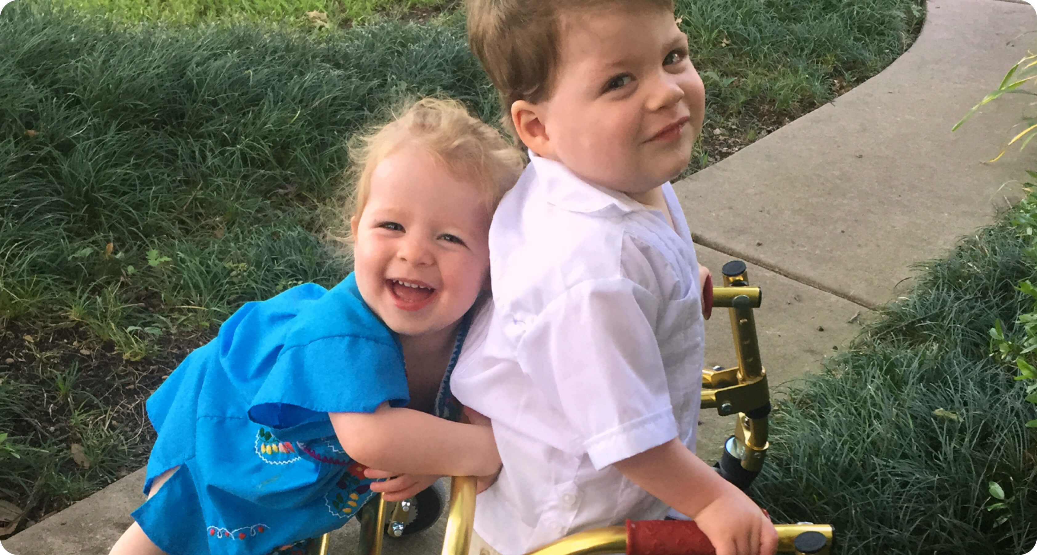Toddler sister hugging twin brother who is using a walker