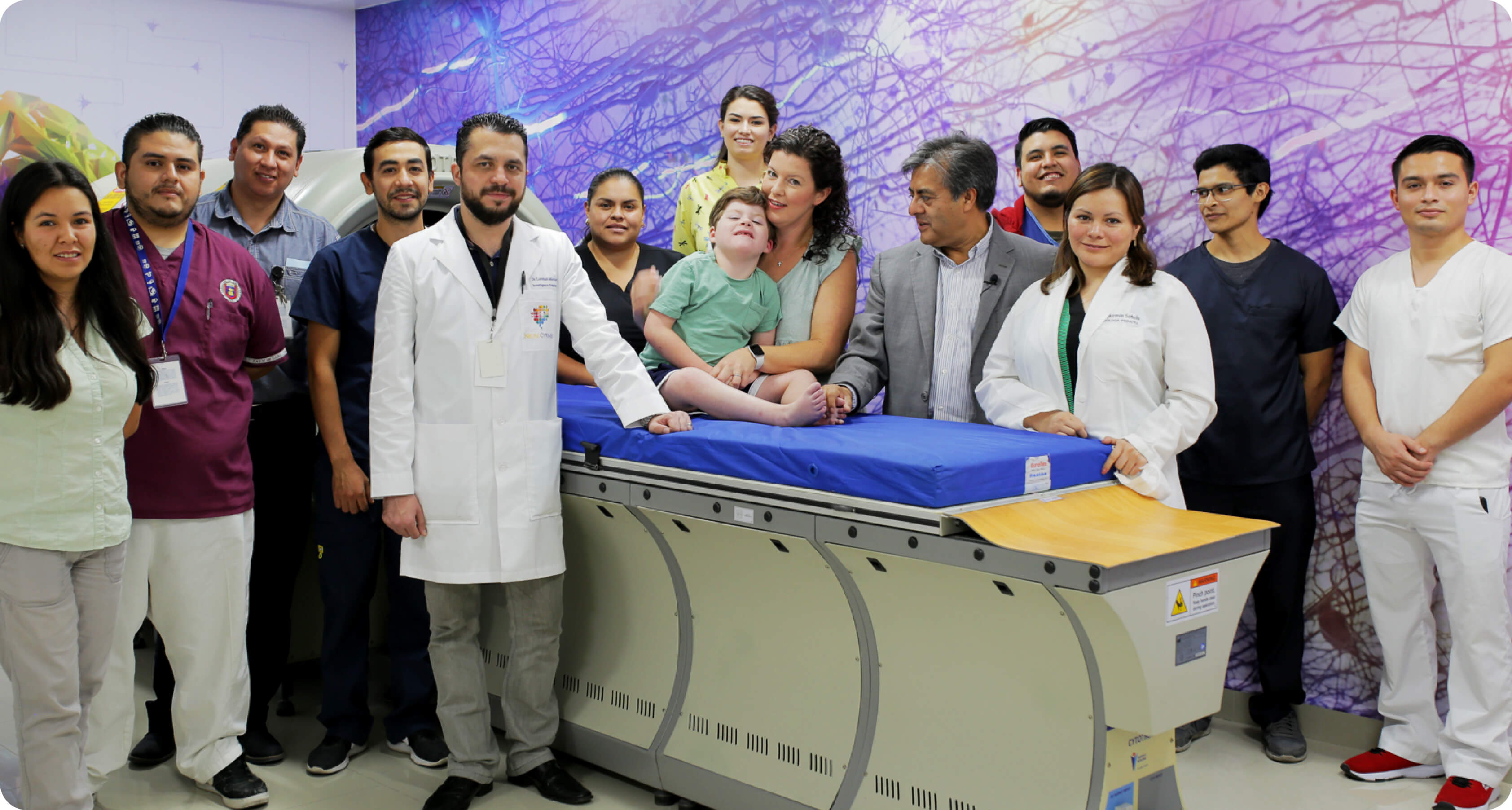 NeuroCytonix clinical team sitting standing with young boy who is sitting on the NeuroCytonix device