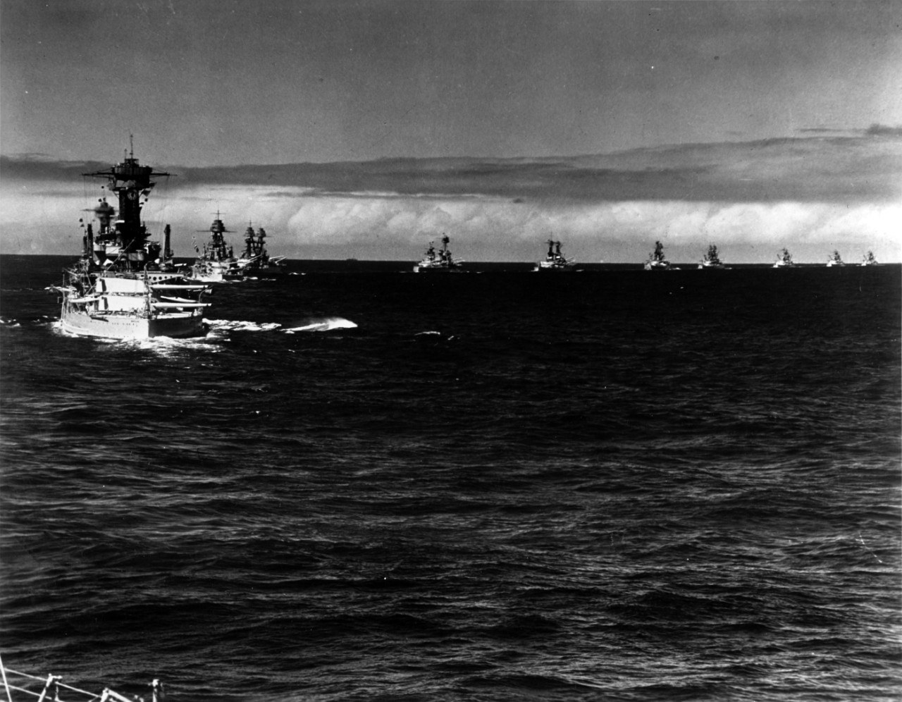 Of the eleven battleships, all making a starboard turn while steaming in column, USS Maryland is at left, closest to the camera