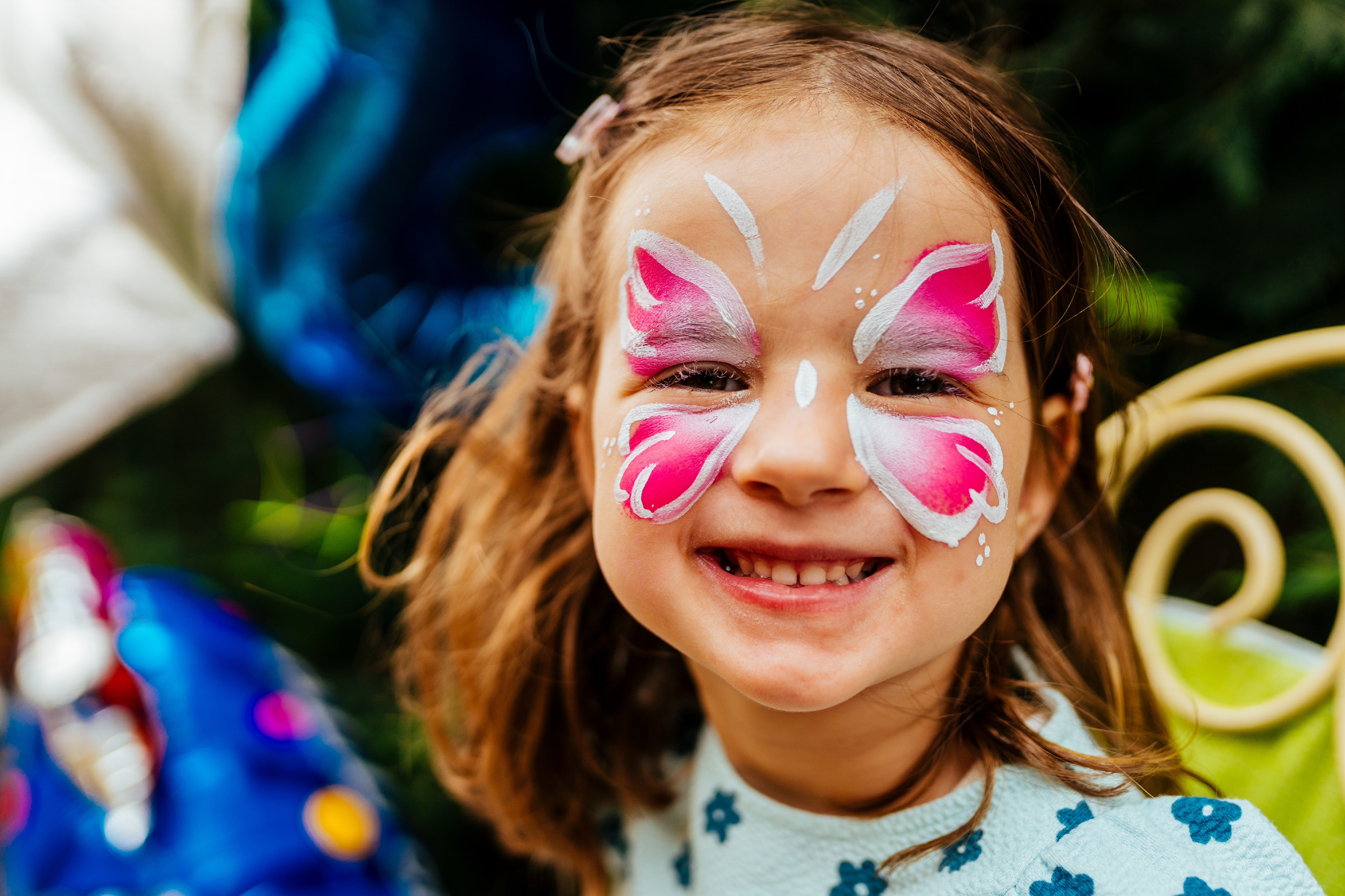Cute little girl having her face painted for kids party. Halloween or carnival family lifestyle Face painting, headshot close up