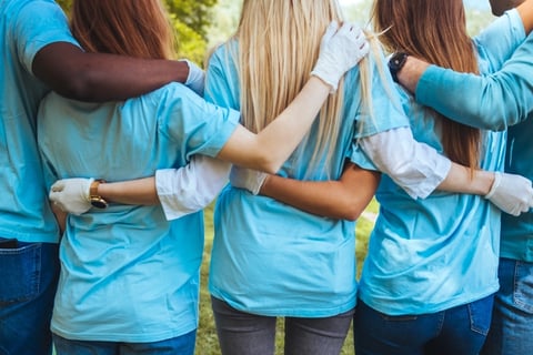 Group of volunteers embracing in park.