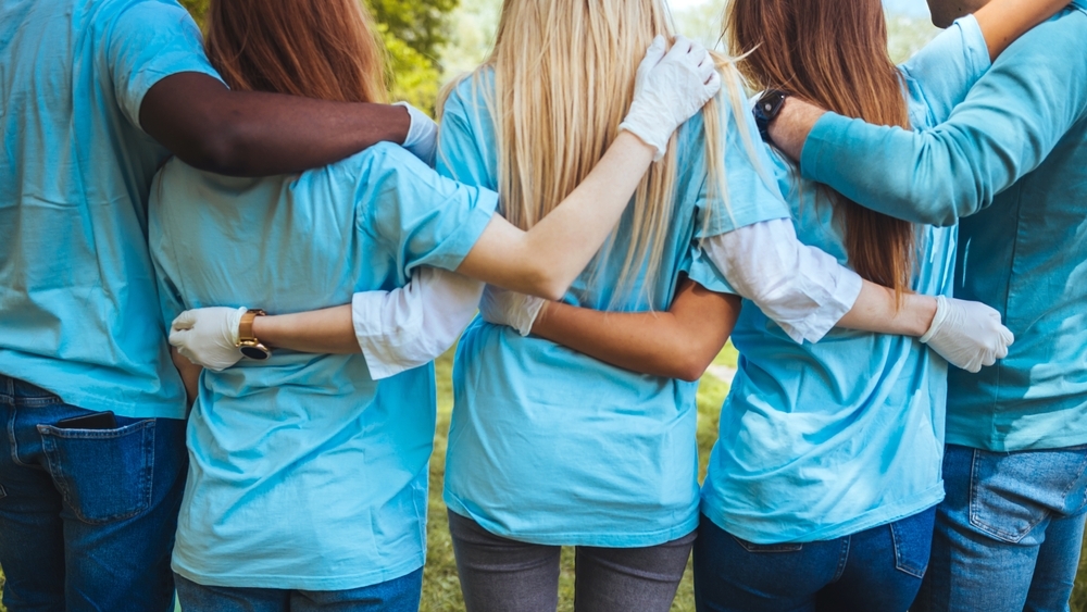 Group of volunteers embracing in park.