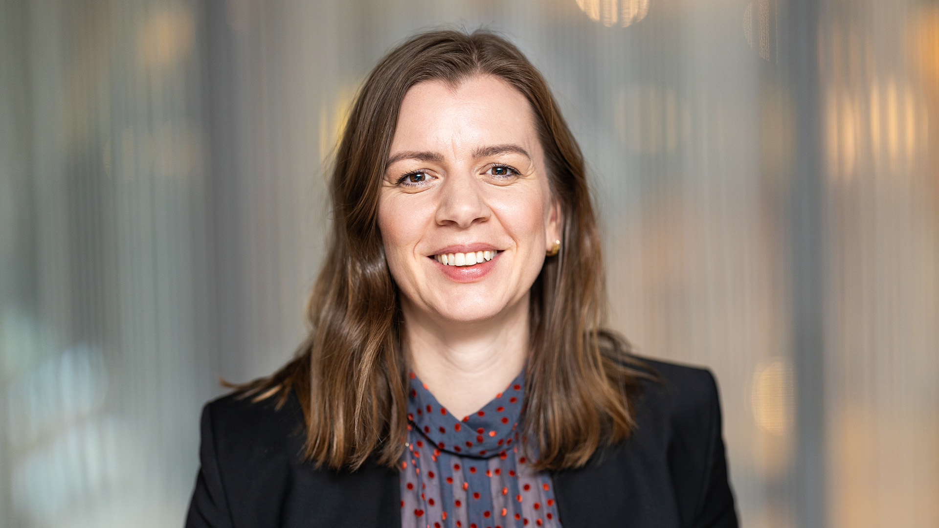 Foto. Kvinne ser mot kamera og smiler