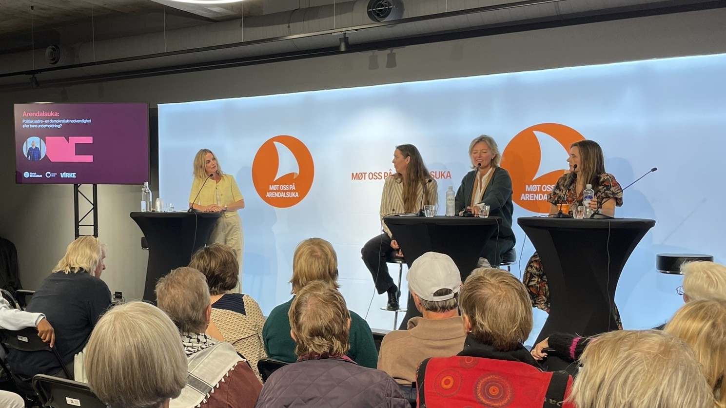 Paneldiskusjon med fire personer ved podier på konferanse om arendalsuka, publikum sitter foran scenen.