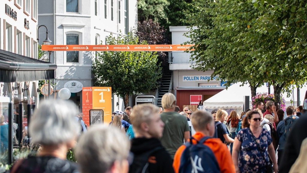 Bilde. Mennesker i en gate med oransje Arendalsuka-banner.