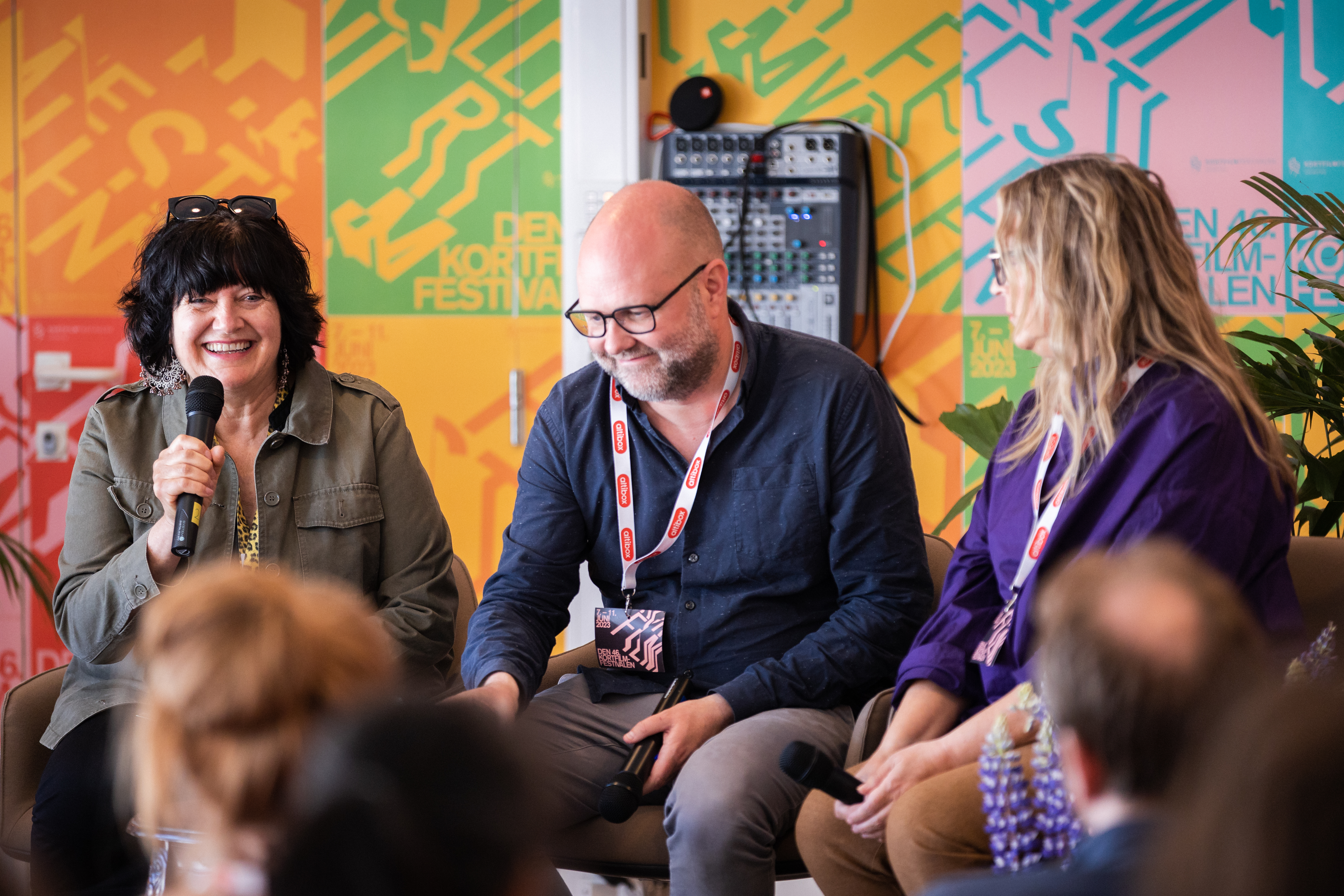 foto. tre personer sitter på scene med mikrofon foran vegg med logo Kortfilmfestivalen